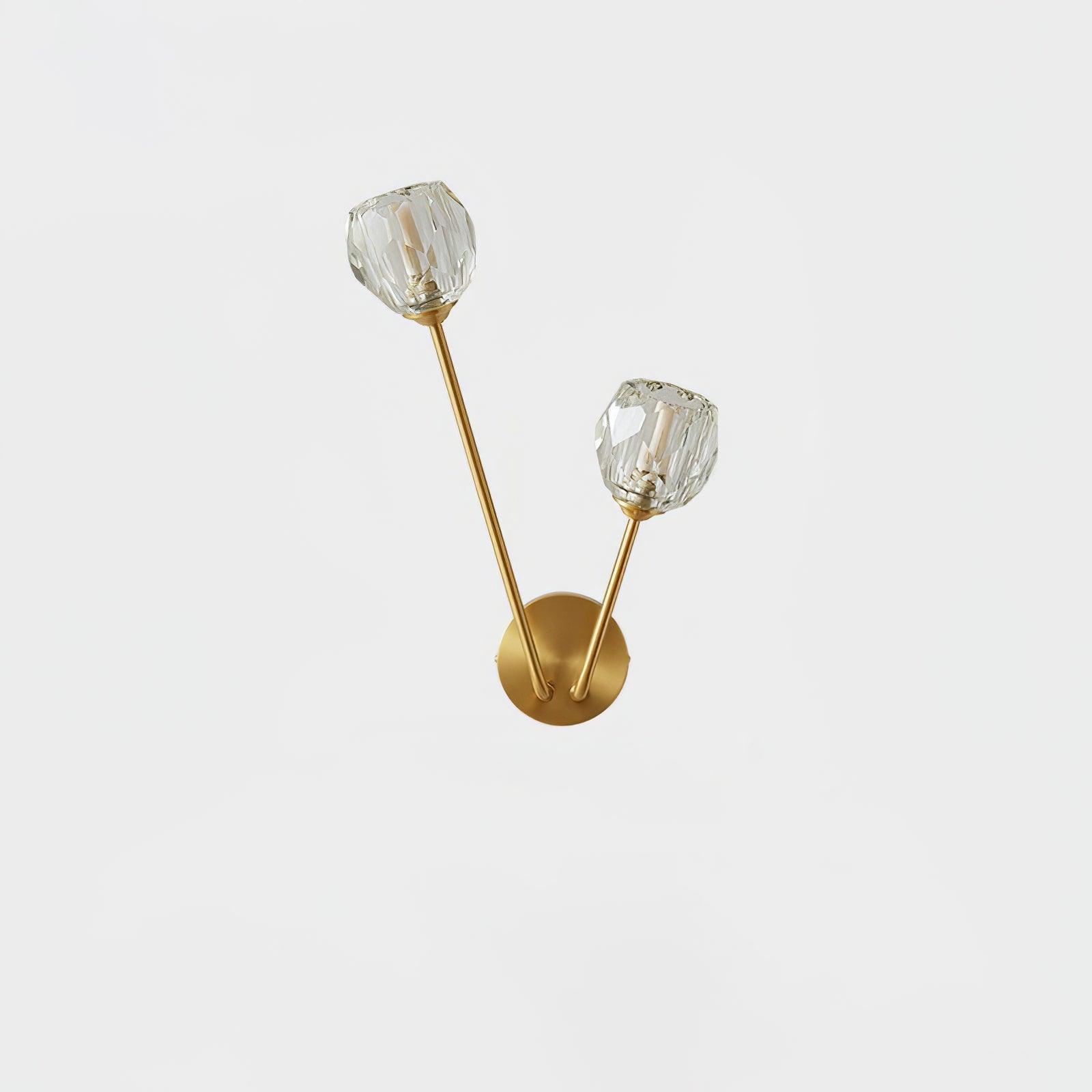 Unlit clear faceted glass shades with visible bulb inserts, unequal brass-tone stems and round wall plate