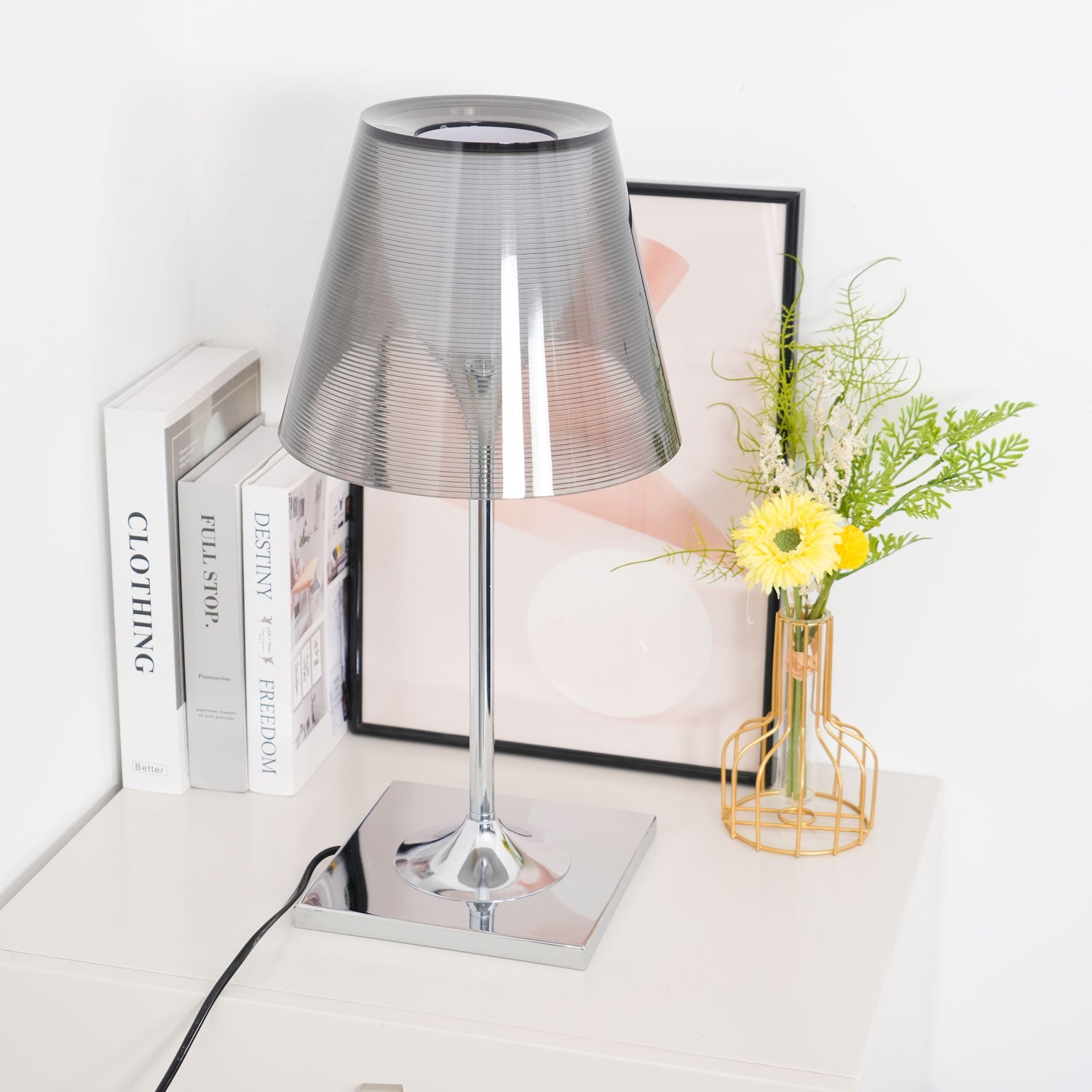 Smoke grey Chrome Prism shade unlit beside books and flowers