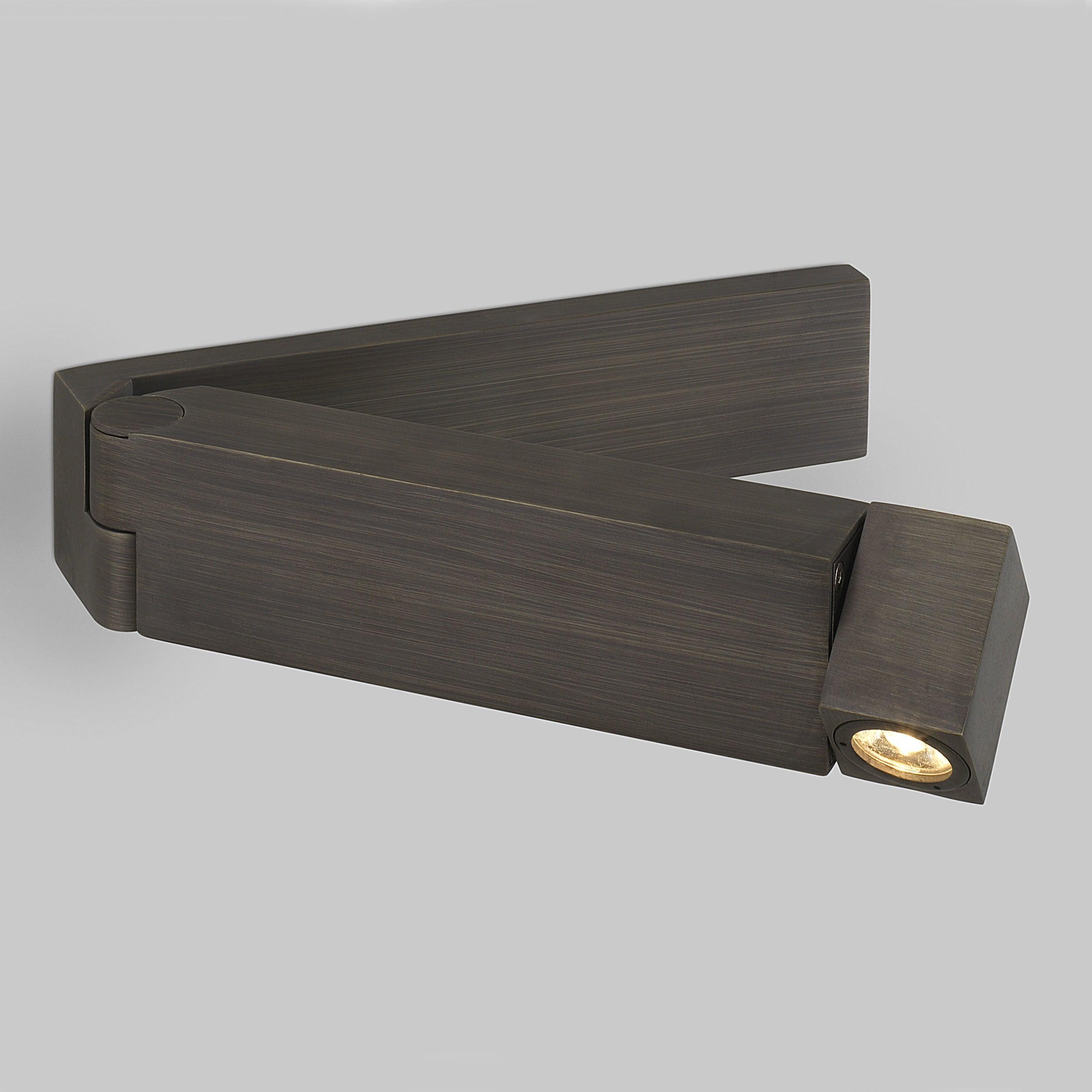 Opposite view of dark fine-grained folding light, with left hinge and lit angular head at right