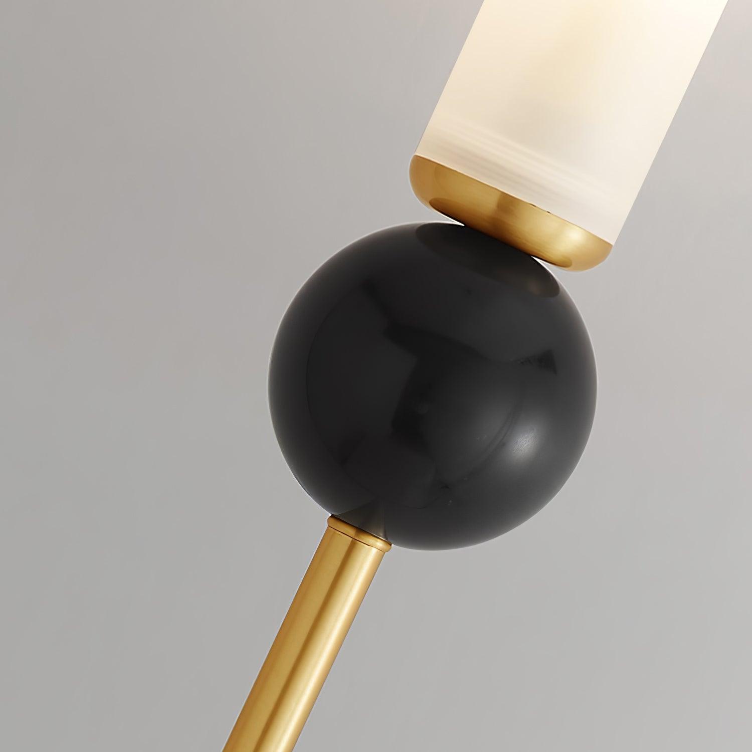 Close-up of dark glossy veined marble sphere between brass lower stem and collar beneath white cylindrical diffuser