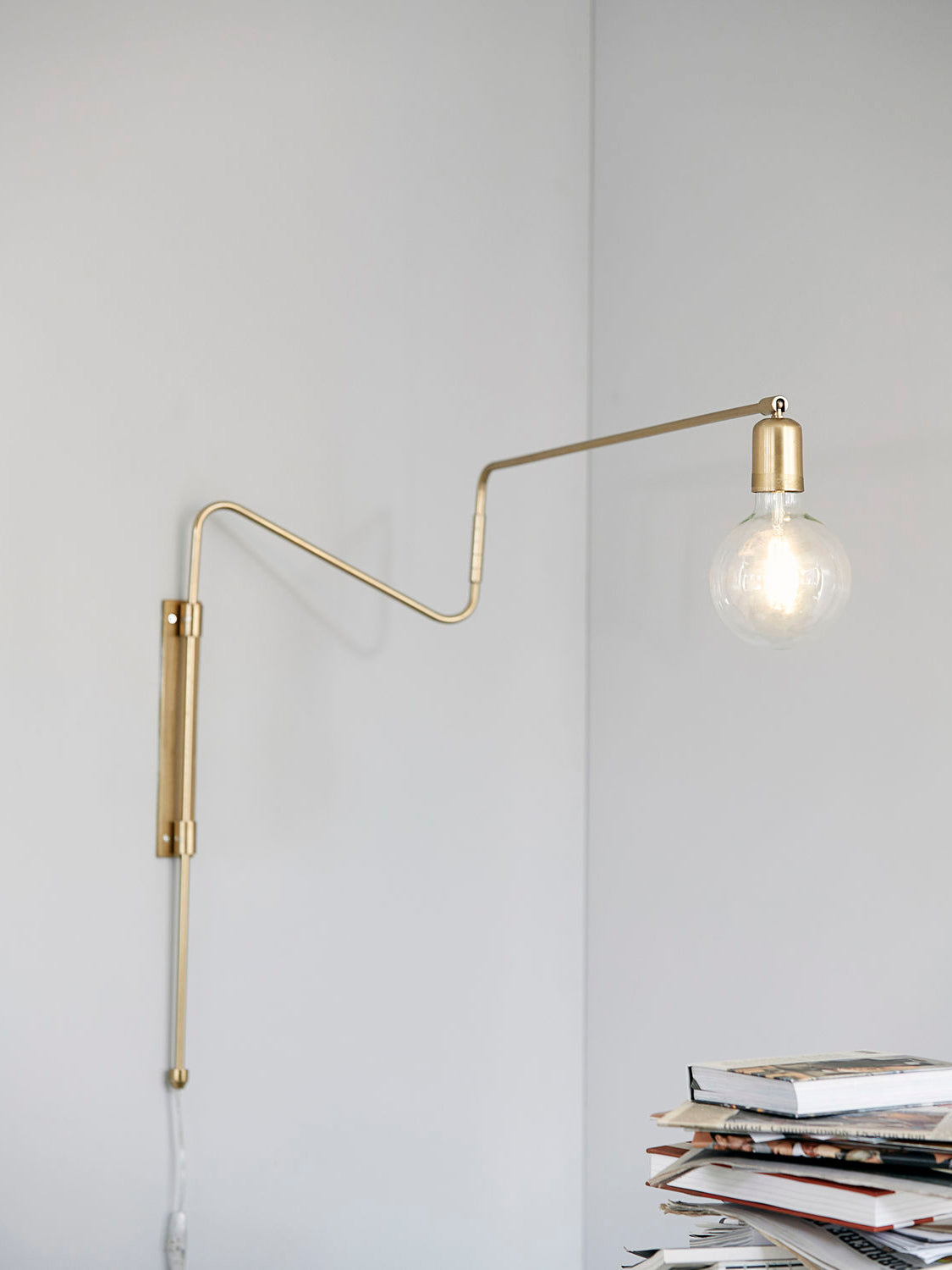 Brass wall lamp above a stack of books