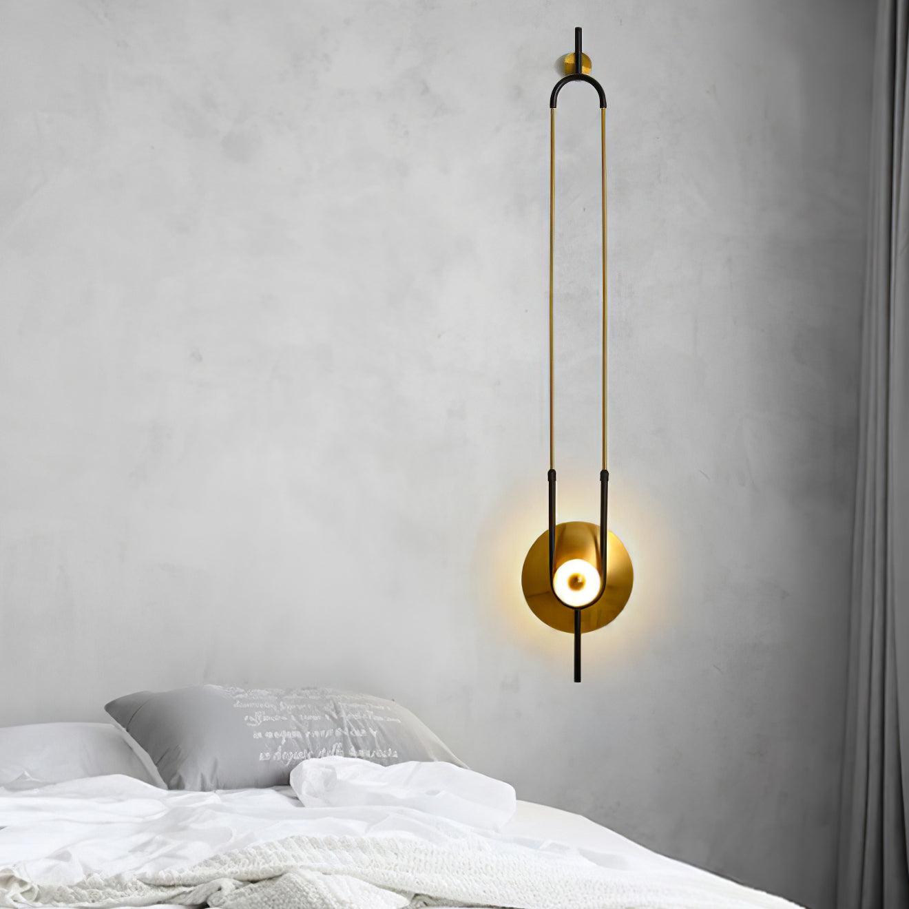Tall lit wall light above white bed and grey printed pillow, beside a dark curtain on textured pale wall