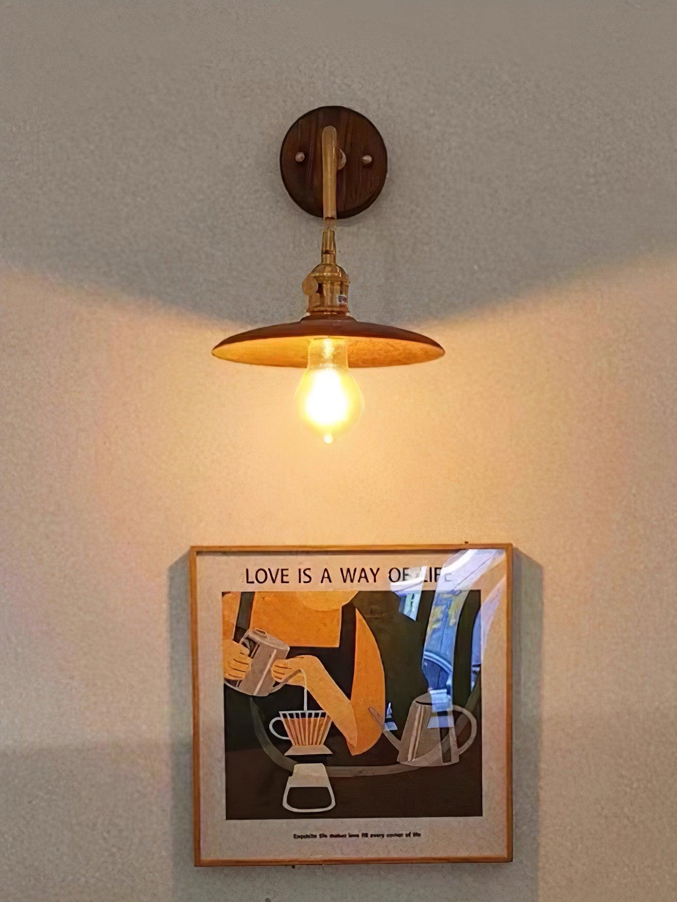 Front view from below of walnut wall light above coffee illustration, bright bulb and short brass arm