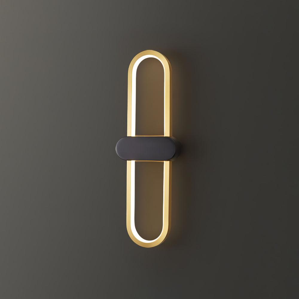 Isolated gold-loop and black-centre wall light glowing against a grey background