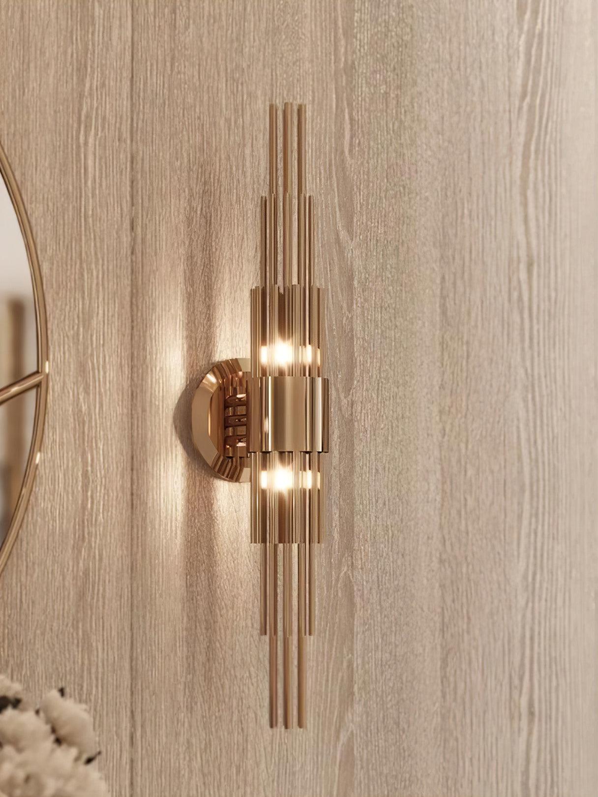 Close room view of a gold stepped-tube wall light beside a mirror on a textured wall