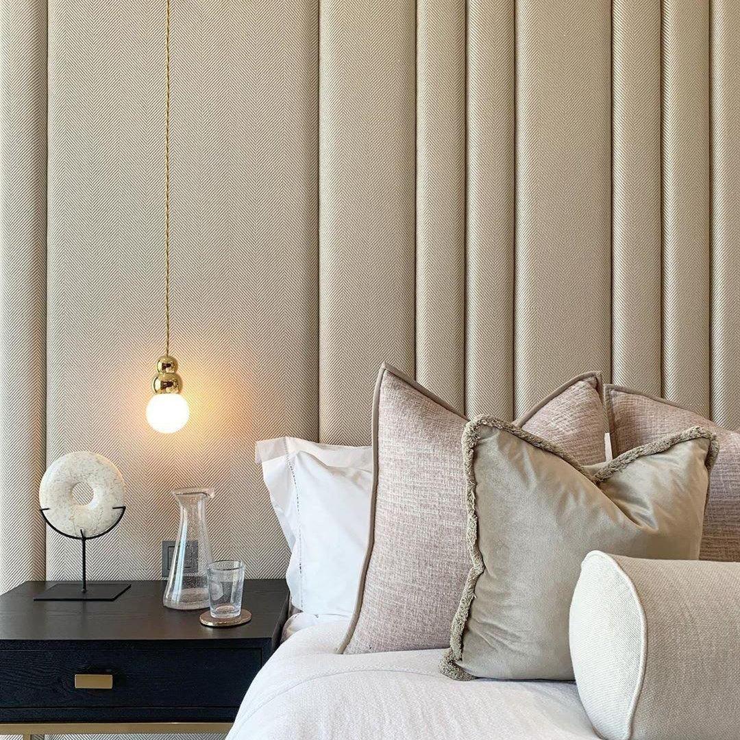 Gold suspended globe light beside a bed