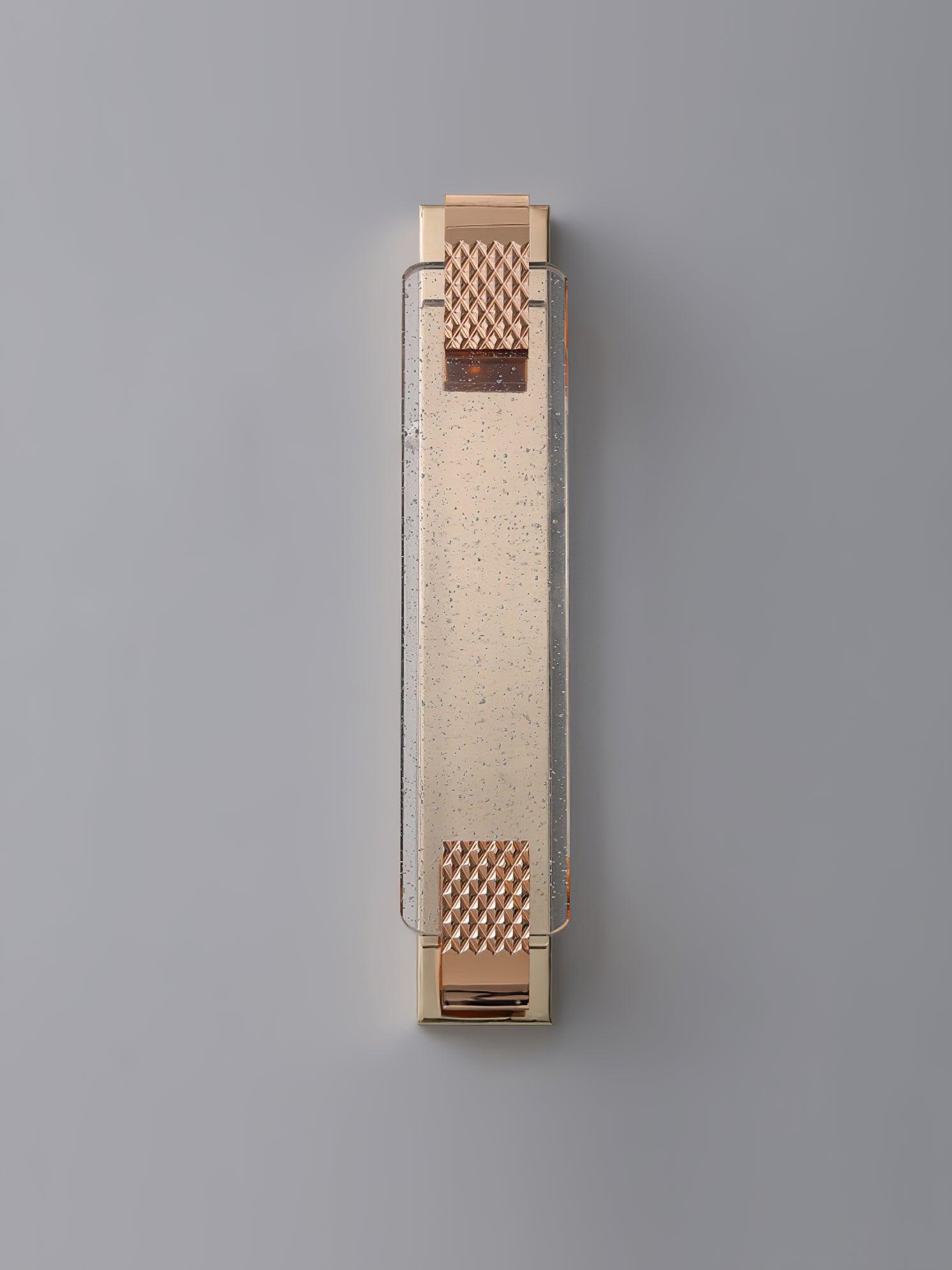 Front view of an unlit Moet sconce against gray, with clear bubbles and diamond-patterned rose gold end straps