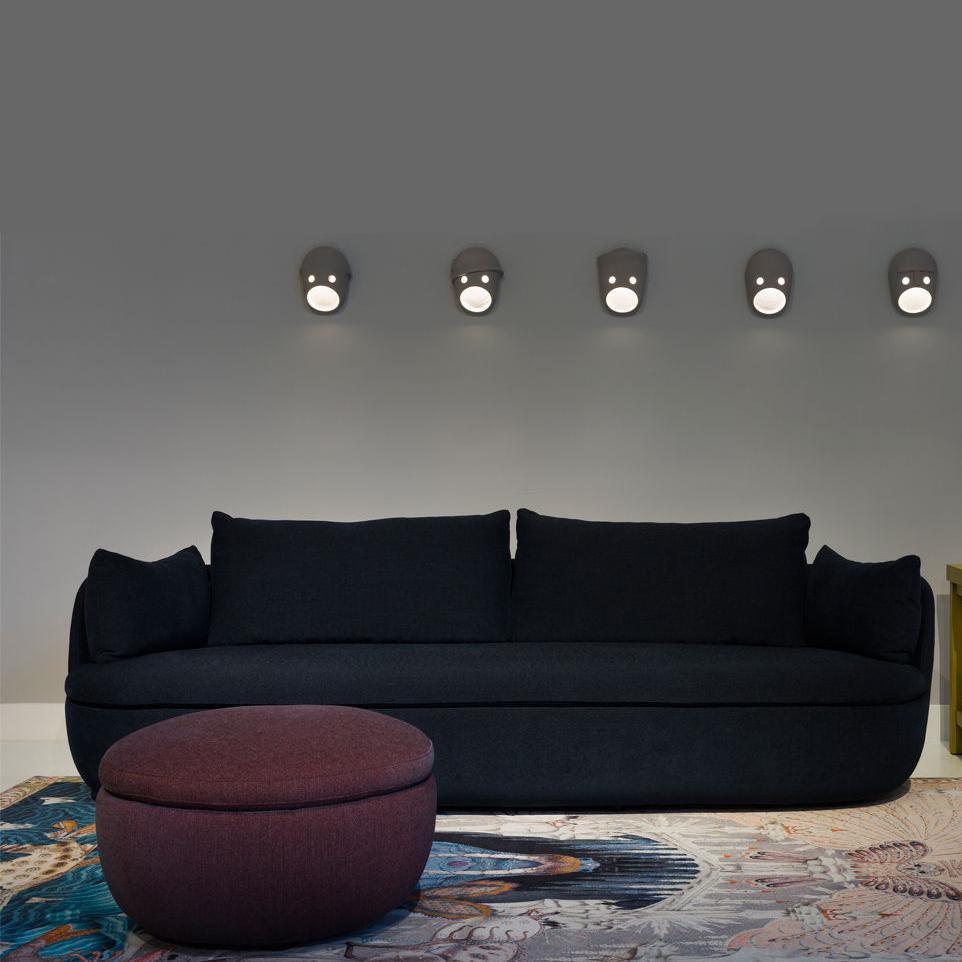 Five illuminated face lights above a dark sofa