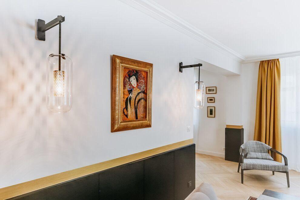 Two glass wall lights flanking framed artwork in a seating area