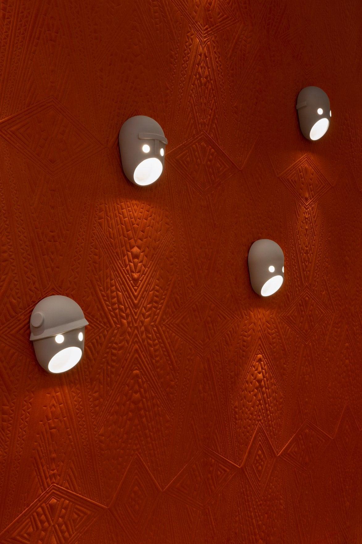 Five illuminated face lights on an orange wall