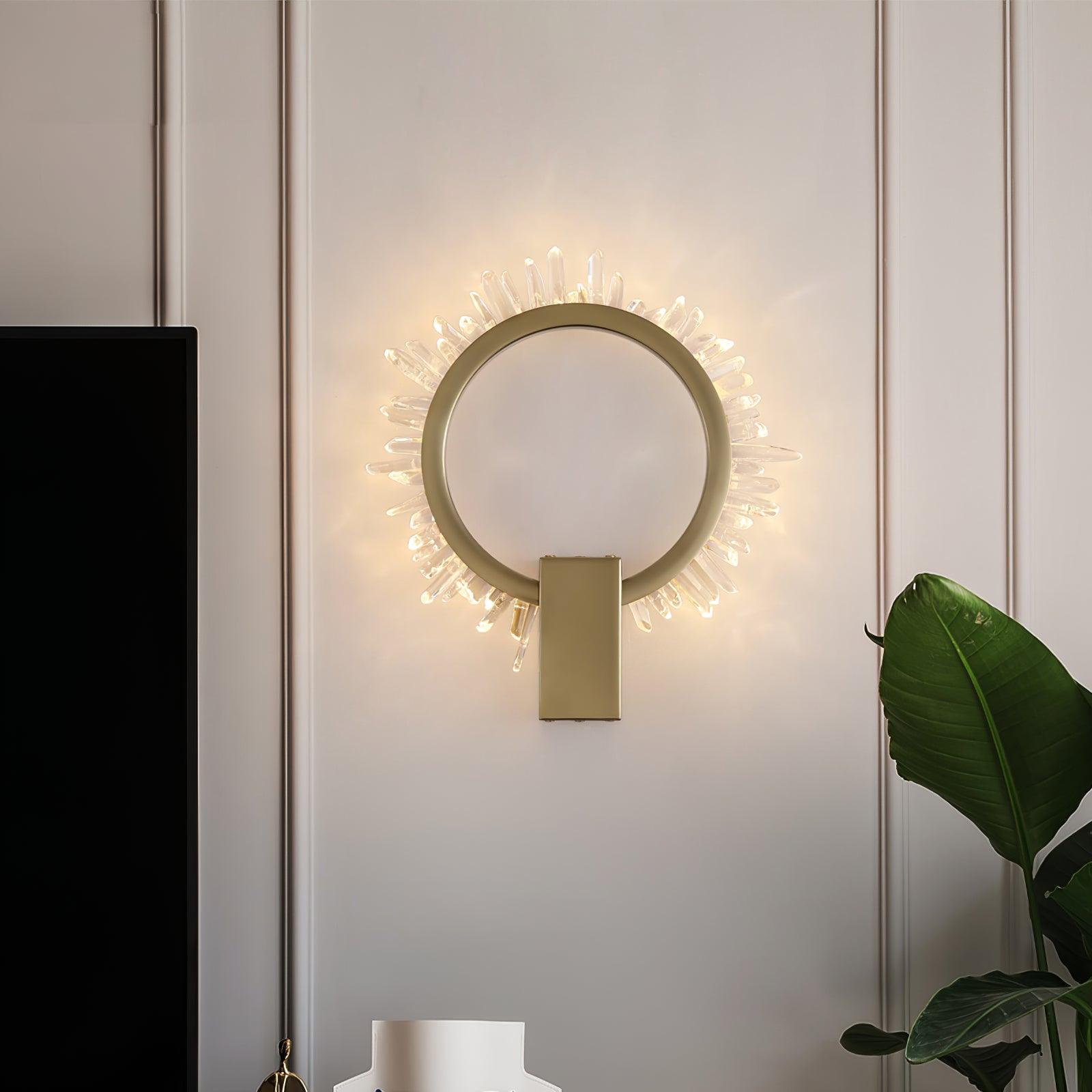 Front view of a lit gold ring with clear crystal points on pale panelling near a large green plant