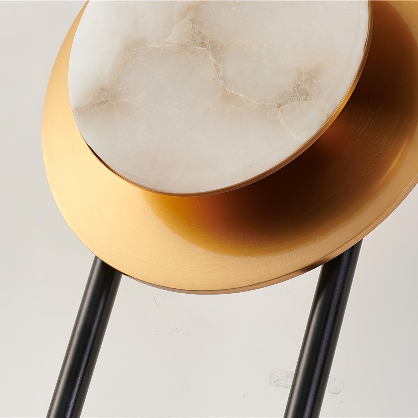 Detail of the veined marble face and thin gold edge in front of the broad brushed gold disc