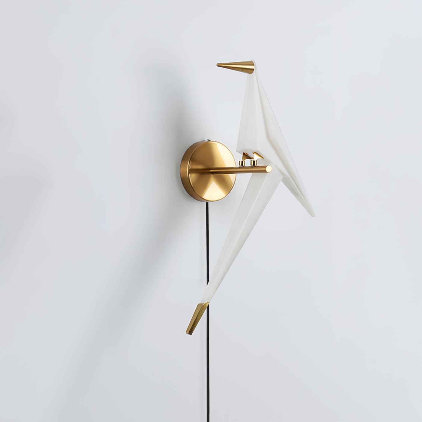 White bird wall light on a Gold arm and round backplate, shown unlit-looking from an angle with its beak facing left
