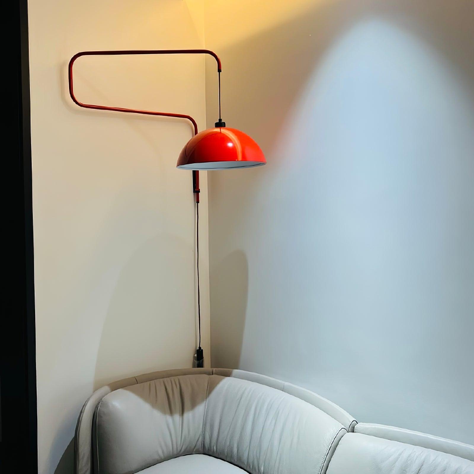 Long-arm red lamp reaching above a curved sofa