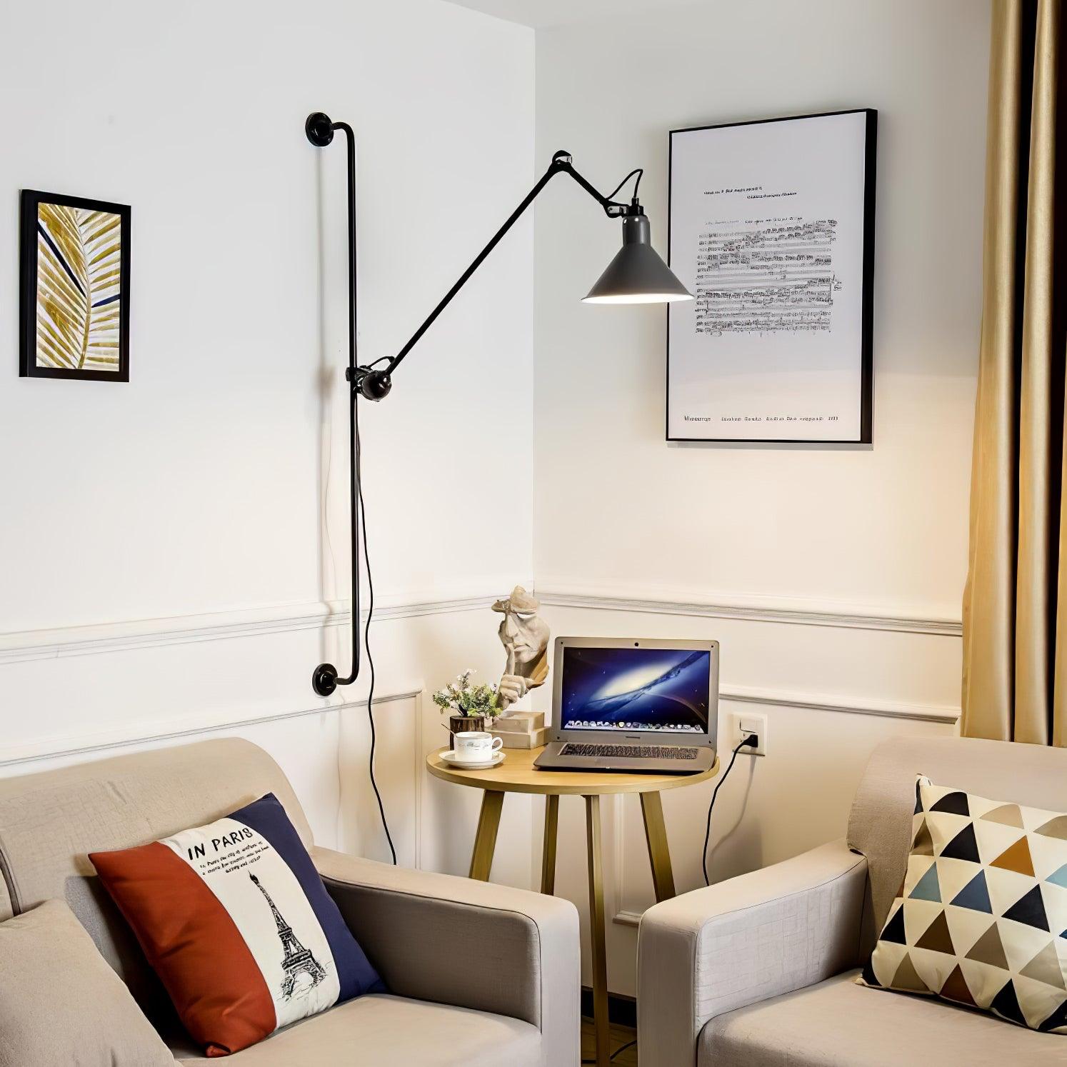 Black conical wall lamp above a small laptop table between two armchairs