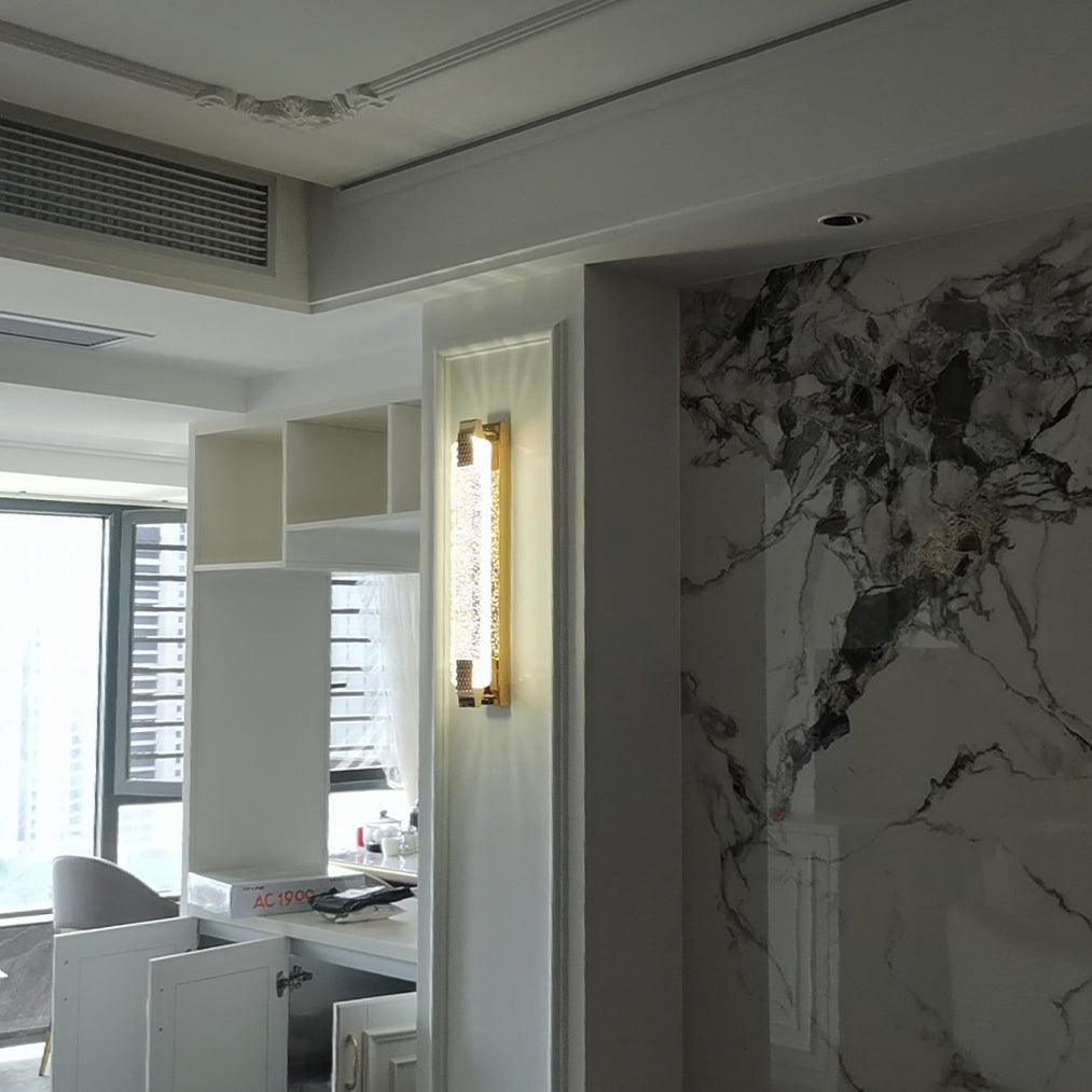 Single Moet sconce on a narrow paneled wall strip beside a marble-look wall and built-in cabinetry