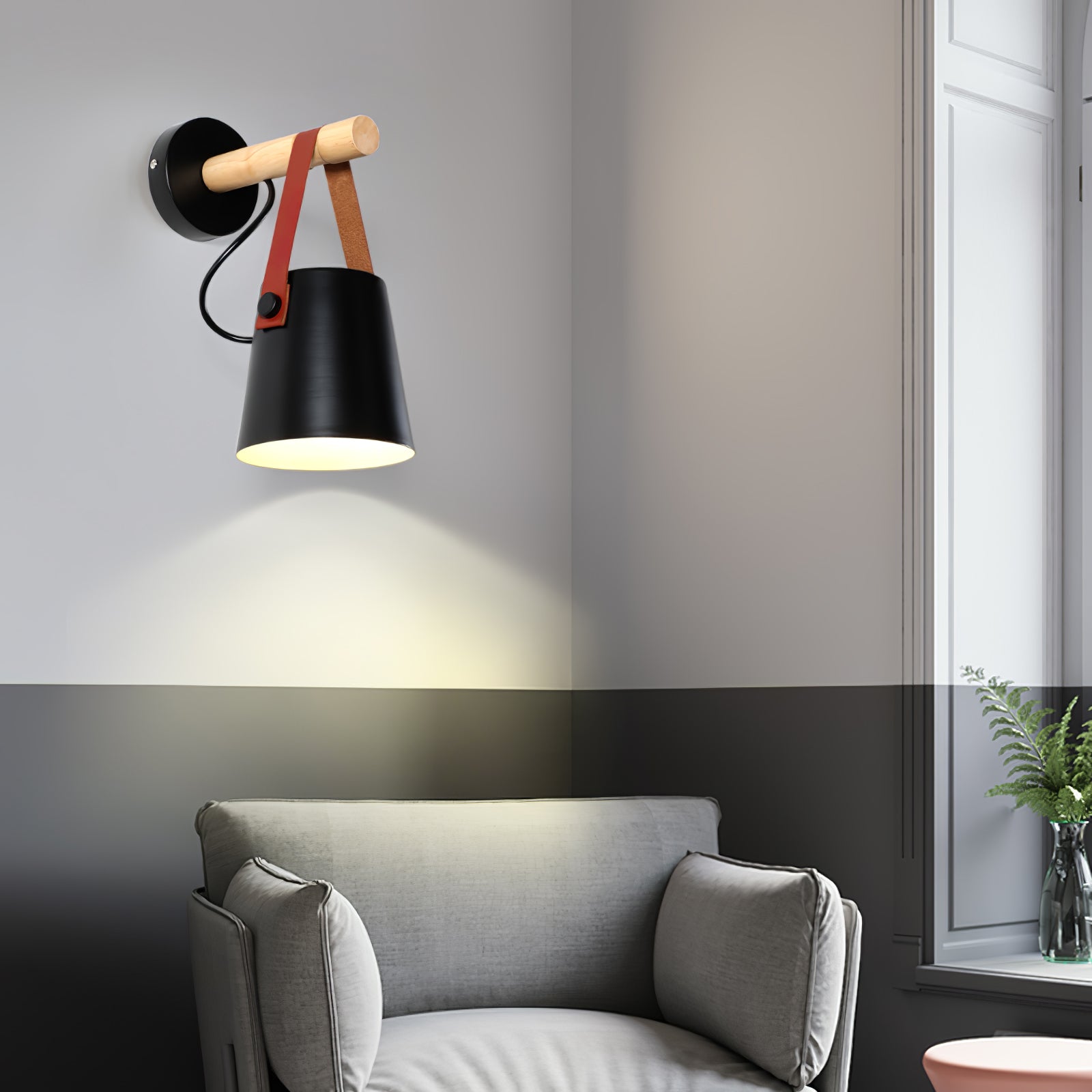 Black wood-and-strap wall light above a grey armchair
