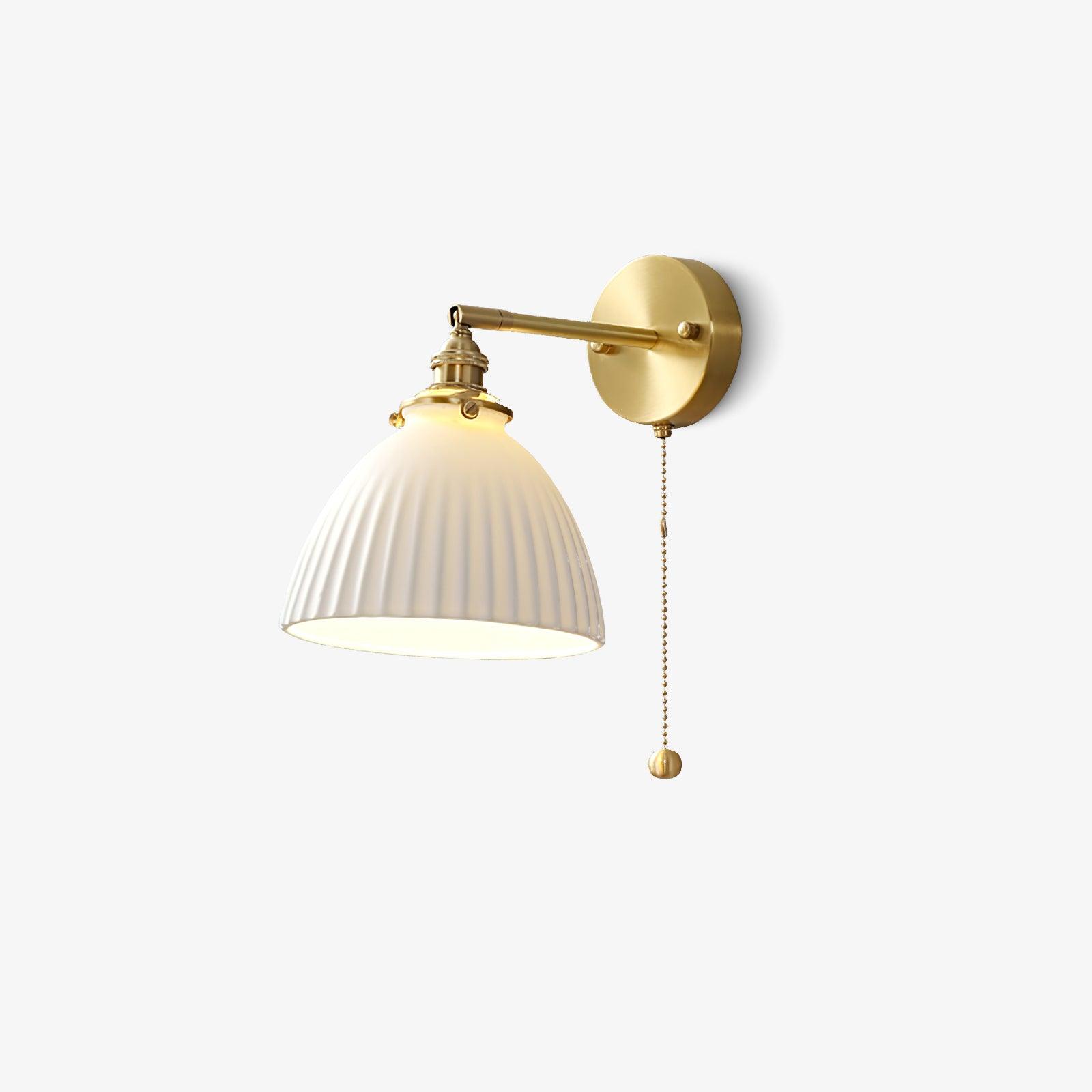 Isolated lit ceramic wall light with arm extending left from a round brass plate and a long round-ended chain