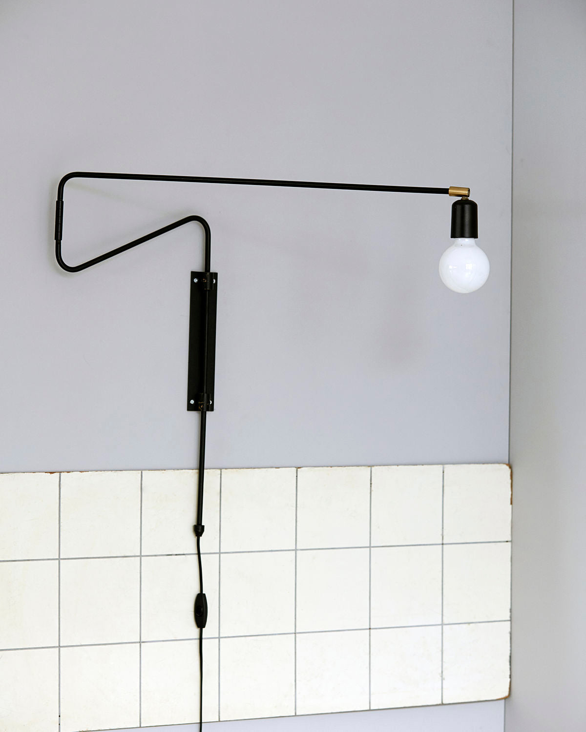 Black extended arm above tiled wall
