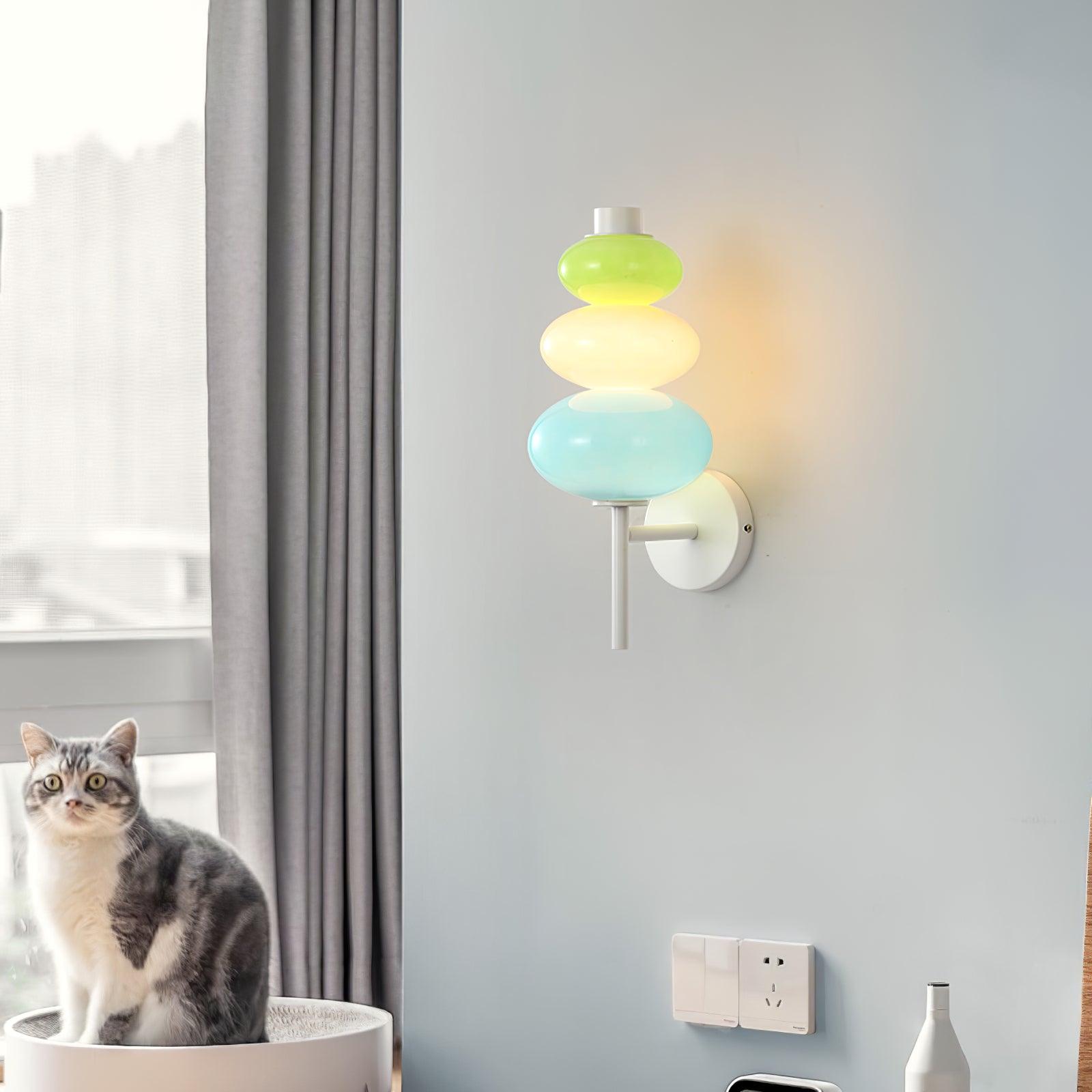 Lit glass wall light beside a curtained window, above a white basket with a cat
