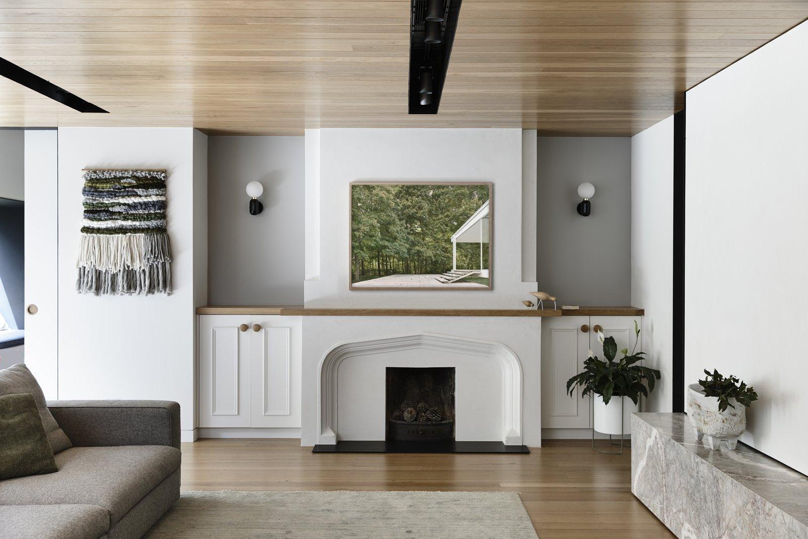 Two black white-globe sconces in alcoves beside fireplace and artwork, white cabinets, plants and wood ceiling