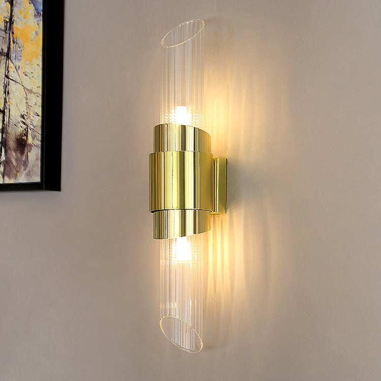 Opposite angled view of lit Gold stepped-centre wall light on grey wall, showing rear mount at right and framed art at left