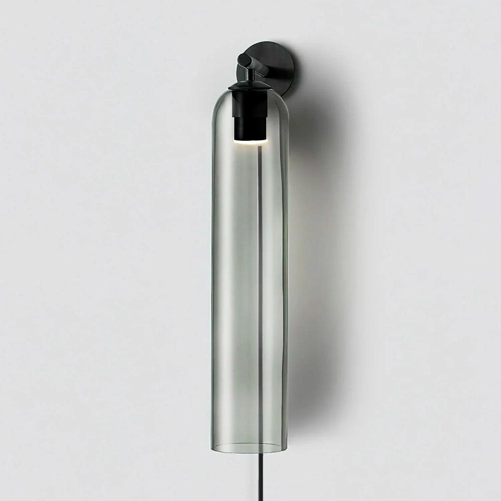 Smoke grey cylindrical glass shade on a black wall light