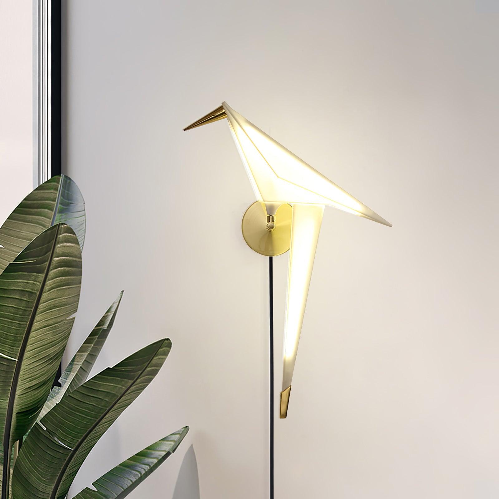 Glowing White bird wall light with Gold beak and round backplate beside green leaves and a window edge, with a cable below