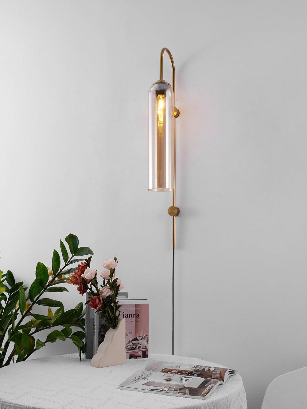 Reflective tube wall lamp beside a vase