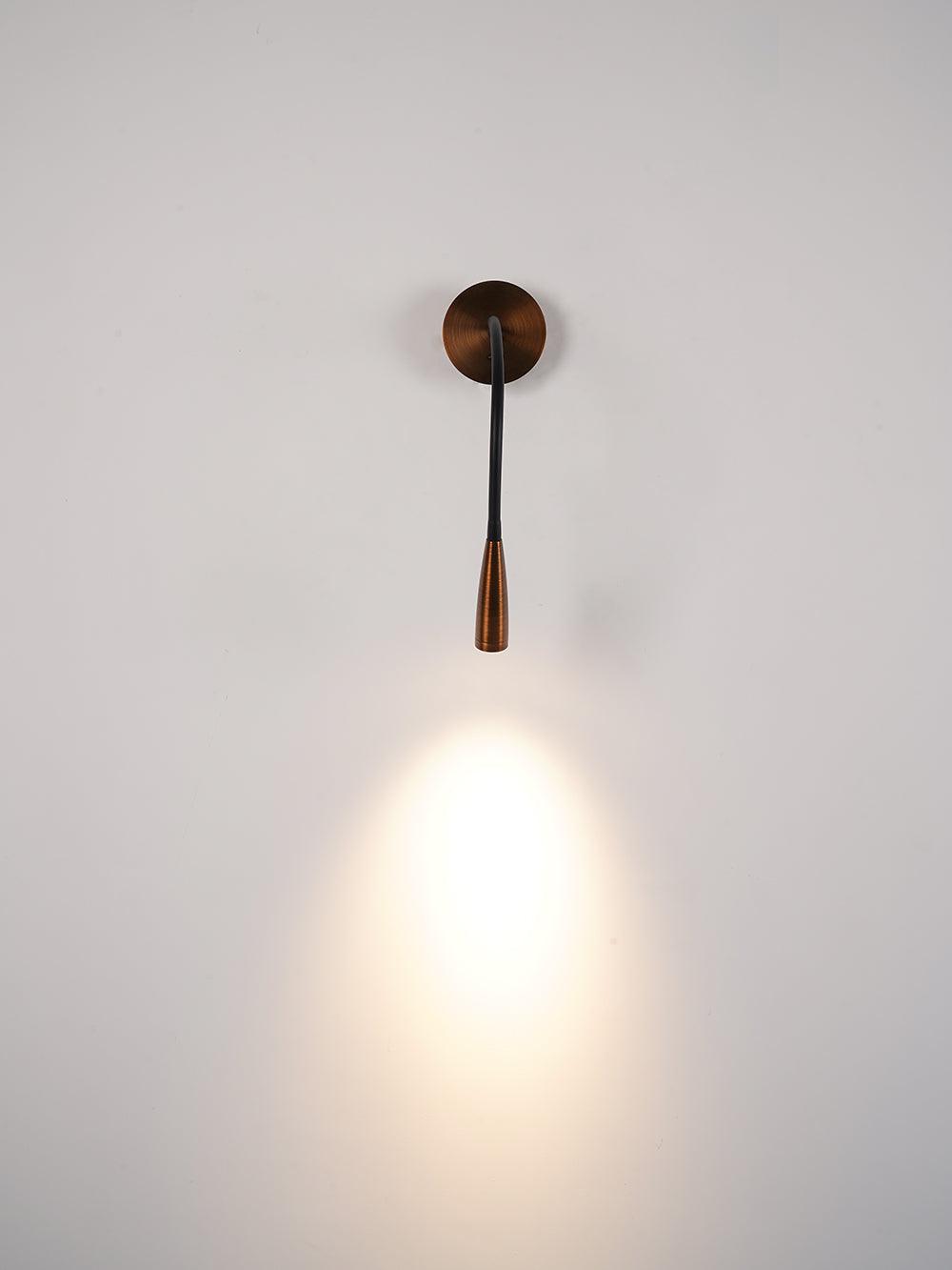 Frontal bronze wall light with straight black arm and narrow head casting bright oval light on pale background
