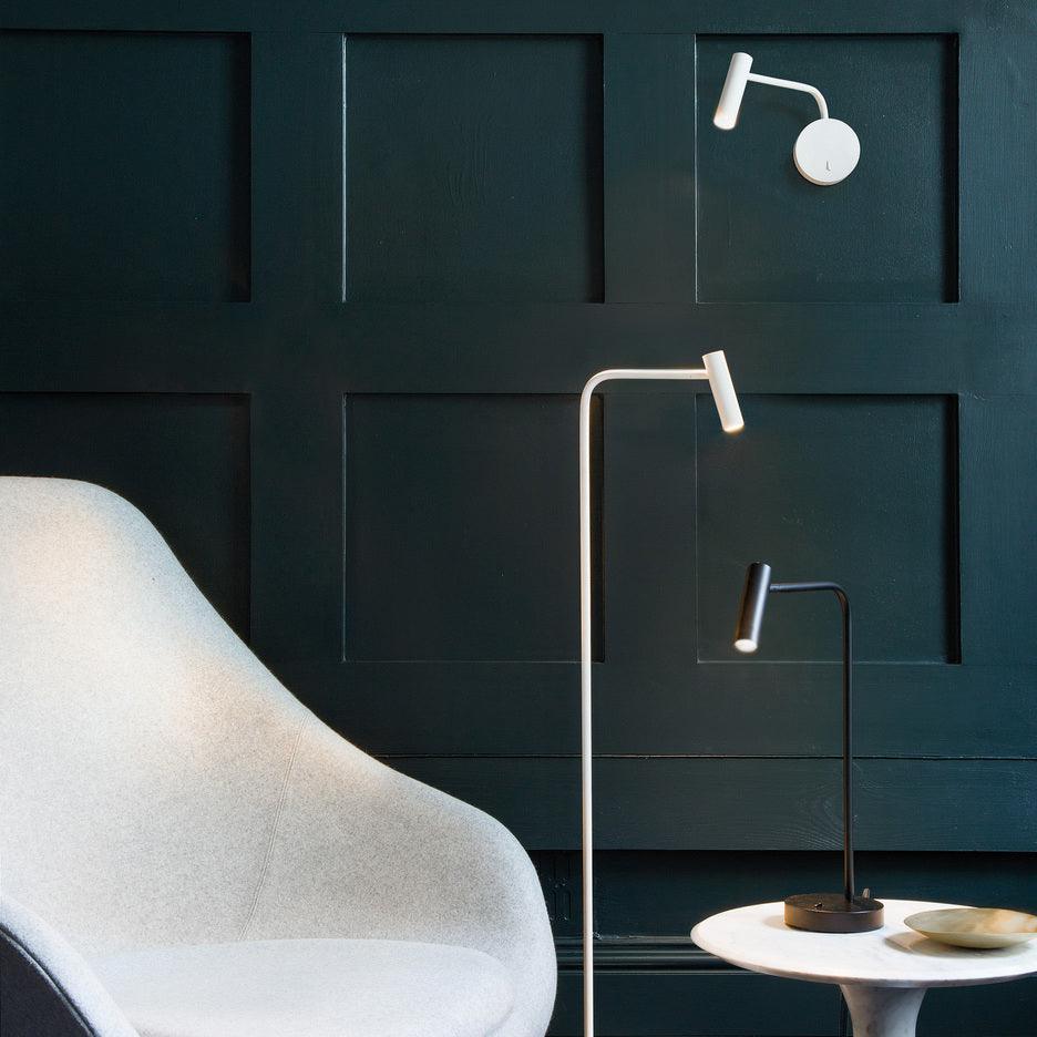 White wall light, floor lamp and table lamp beside a chair against dark panelling