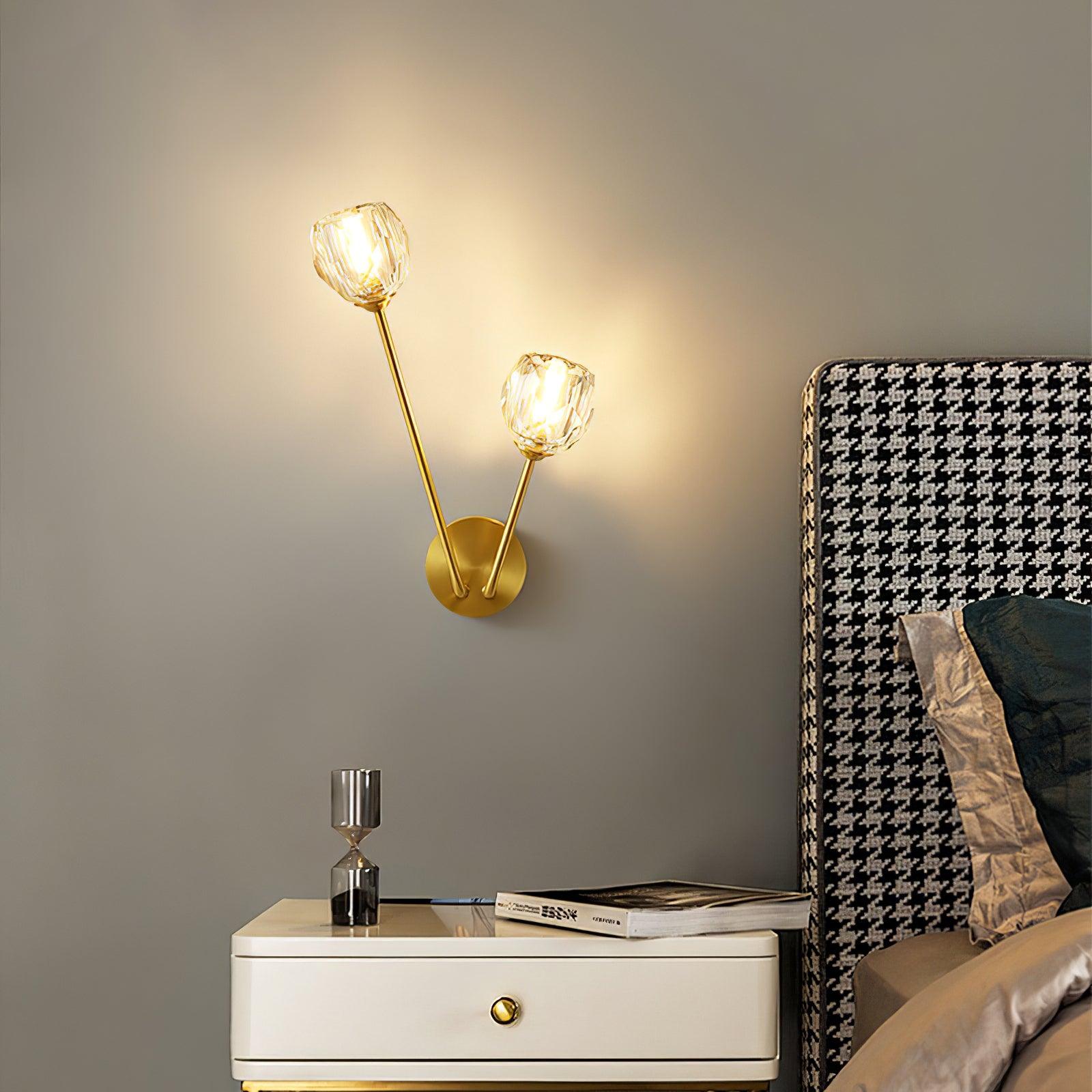 Clear faceted wall light beside a houndstooth headboard, above a white cabinet with books and an hourglass