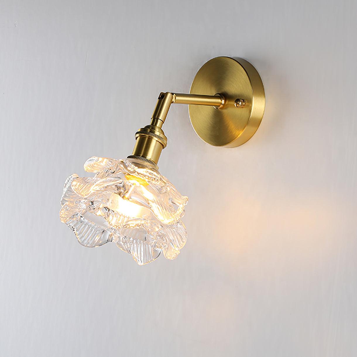 Lit clear glass shade on a brass wall arm