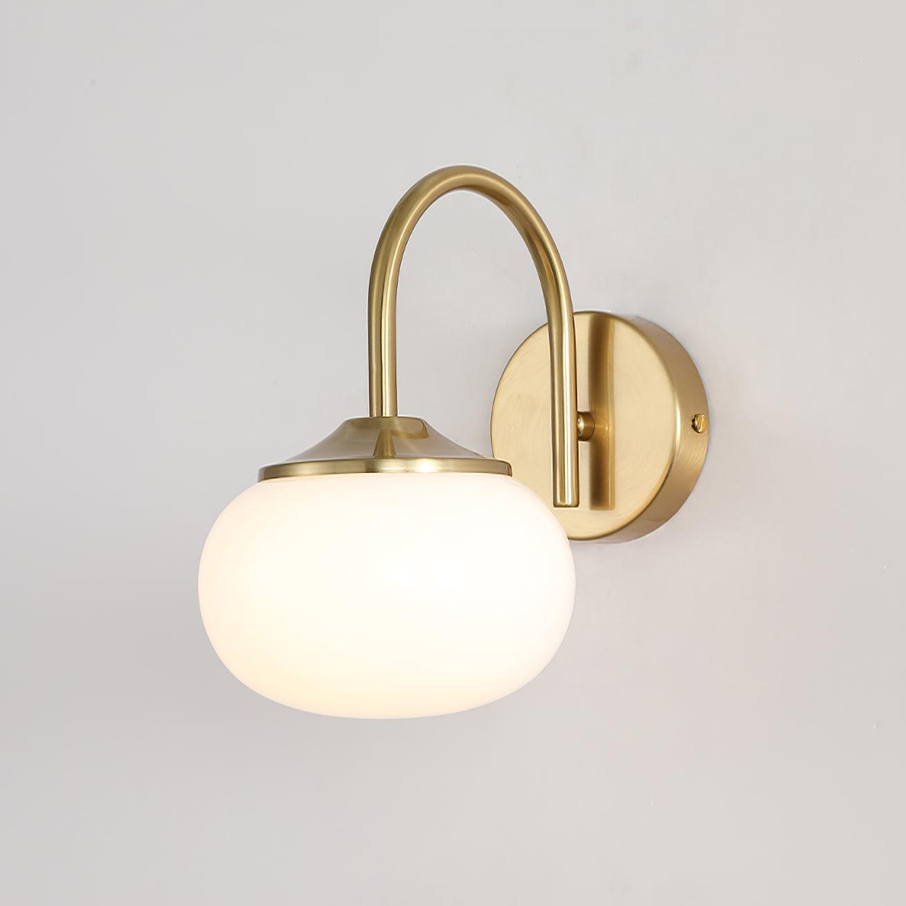 Illuminated pale rounded shade beneath a curved metal arm
