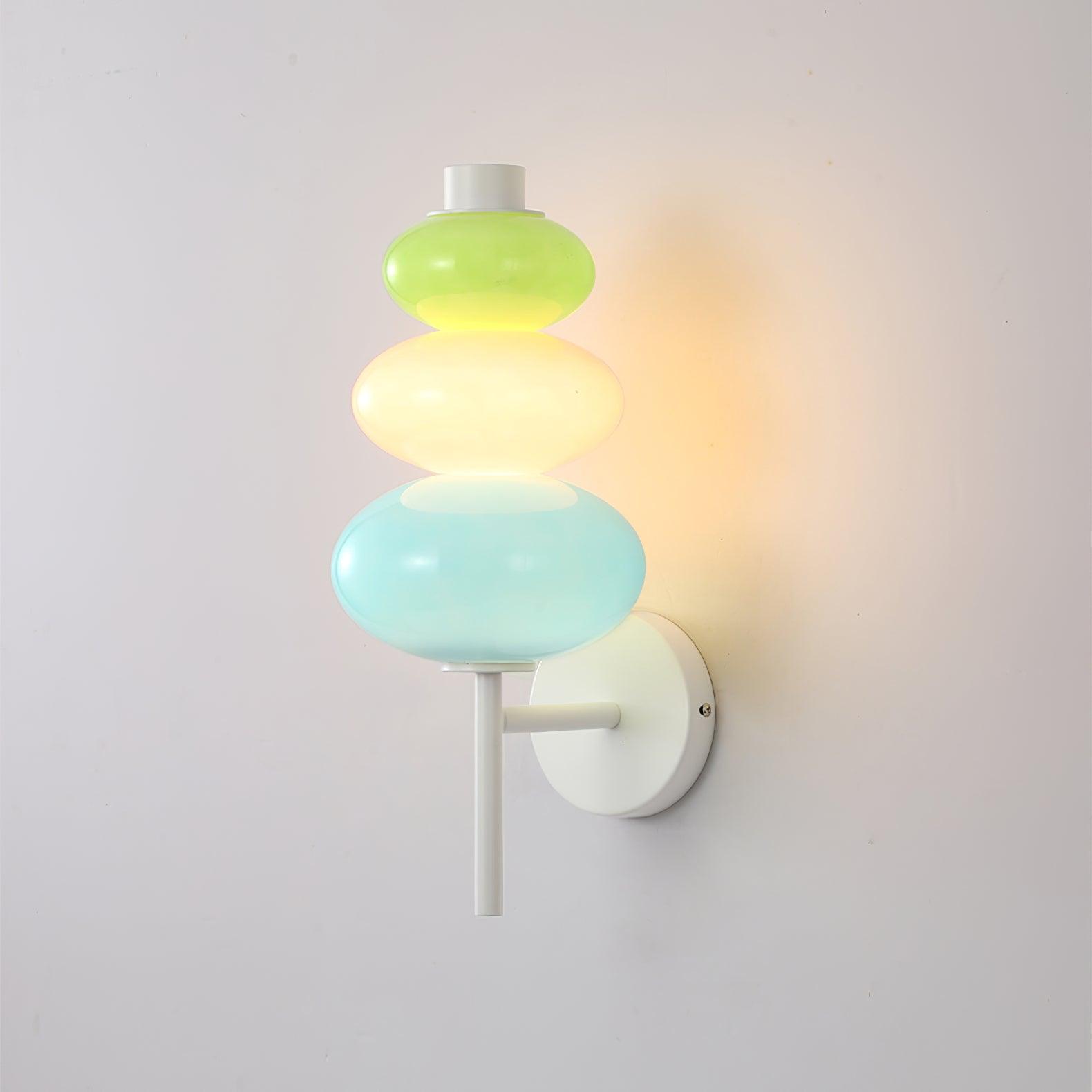 Angled close view of the glowing green, peach-pink and blue glass segments and white support