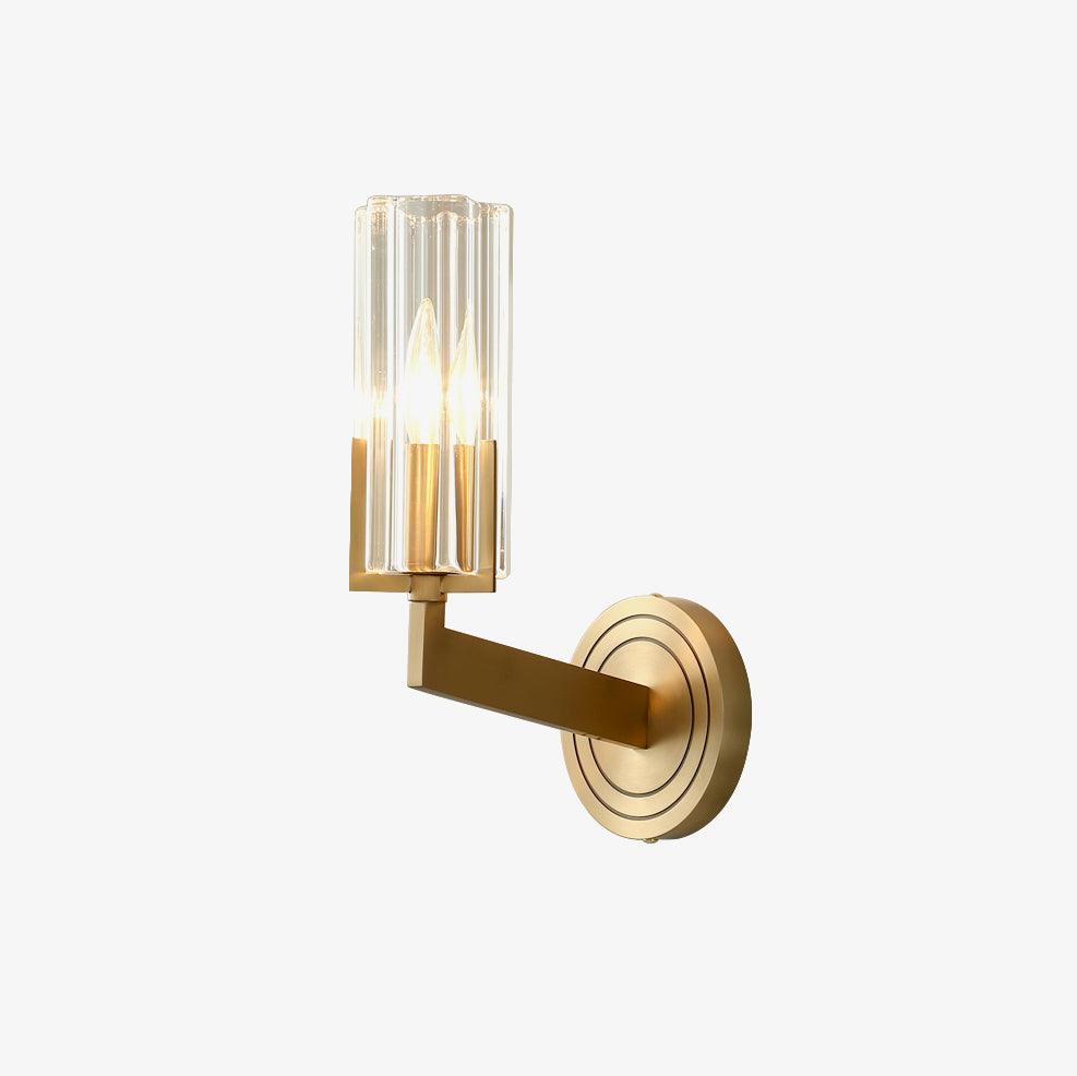 Single-shade Kayla lit on pale background with upright clear fluted tube, angular brass arm and concentric-ring wall plate