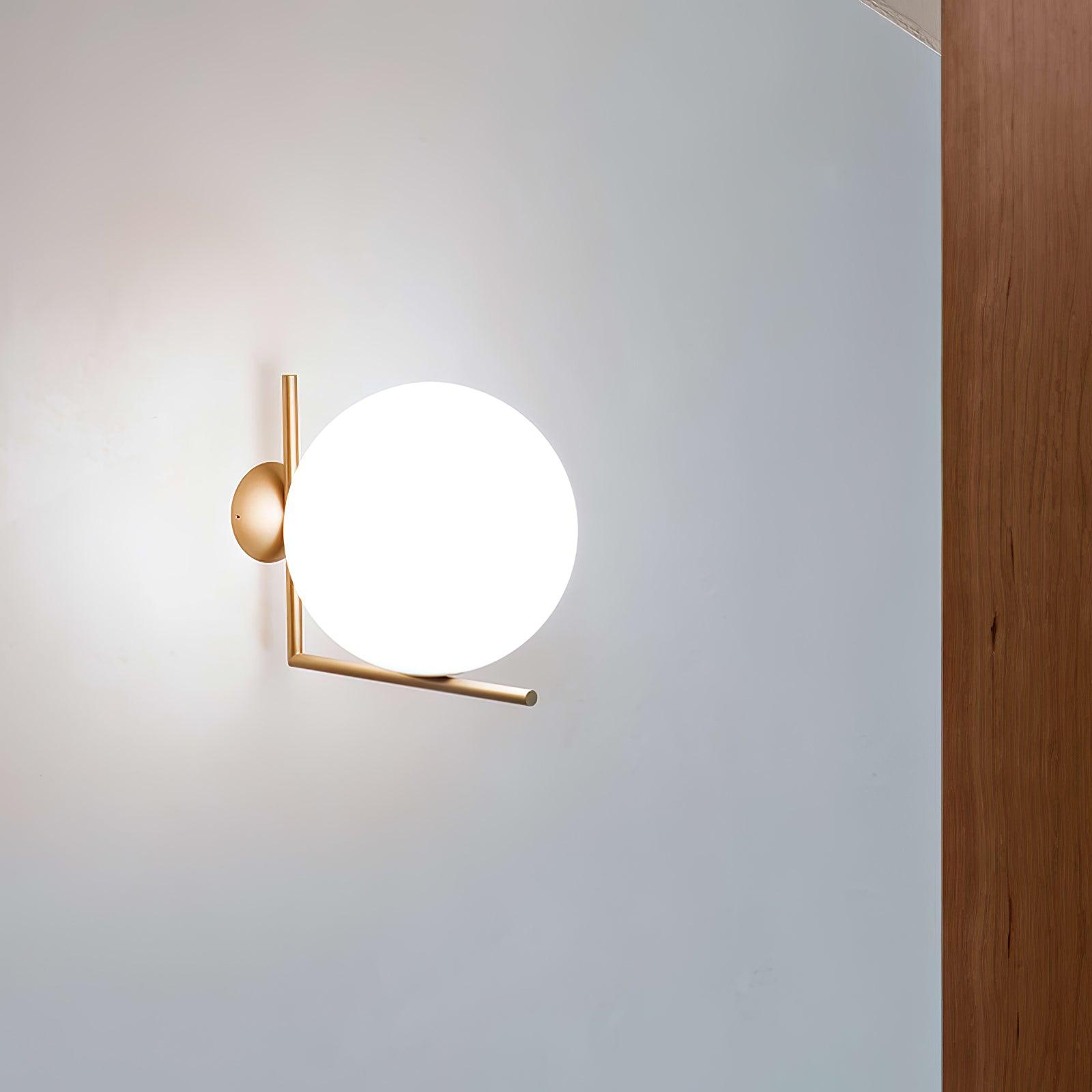 Gold-tone wall light with a glowing white globe beside a wooden wall panel