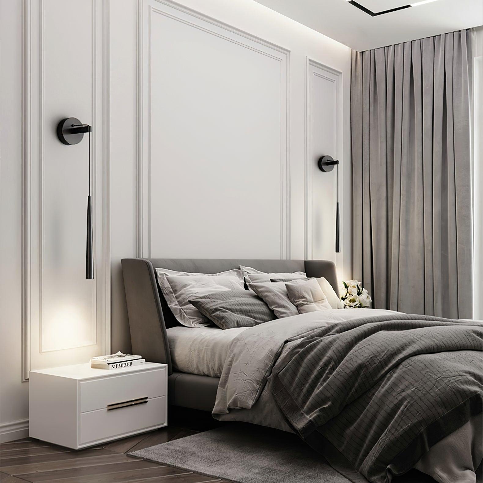 Two separate black plain-ended hanging wall lights on either side of a bed with grey bedding and curtains