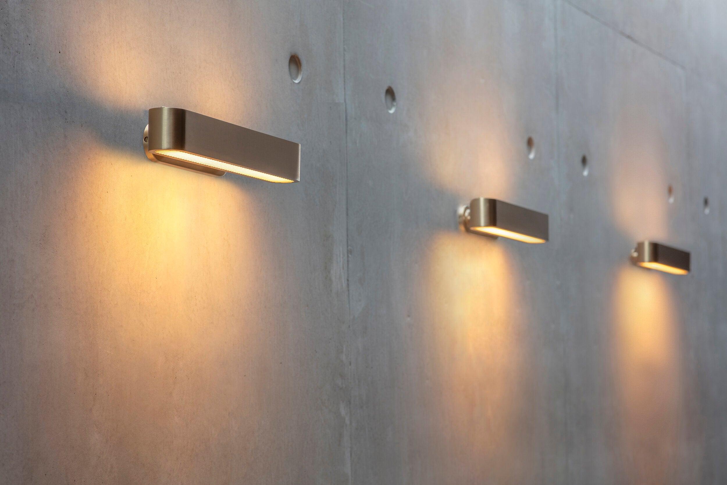 Three horizontal brass fixtures along a textured wall