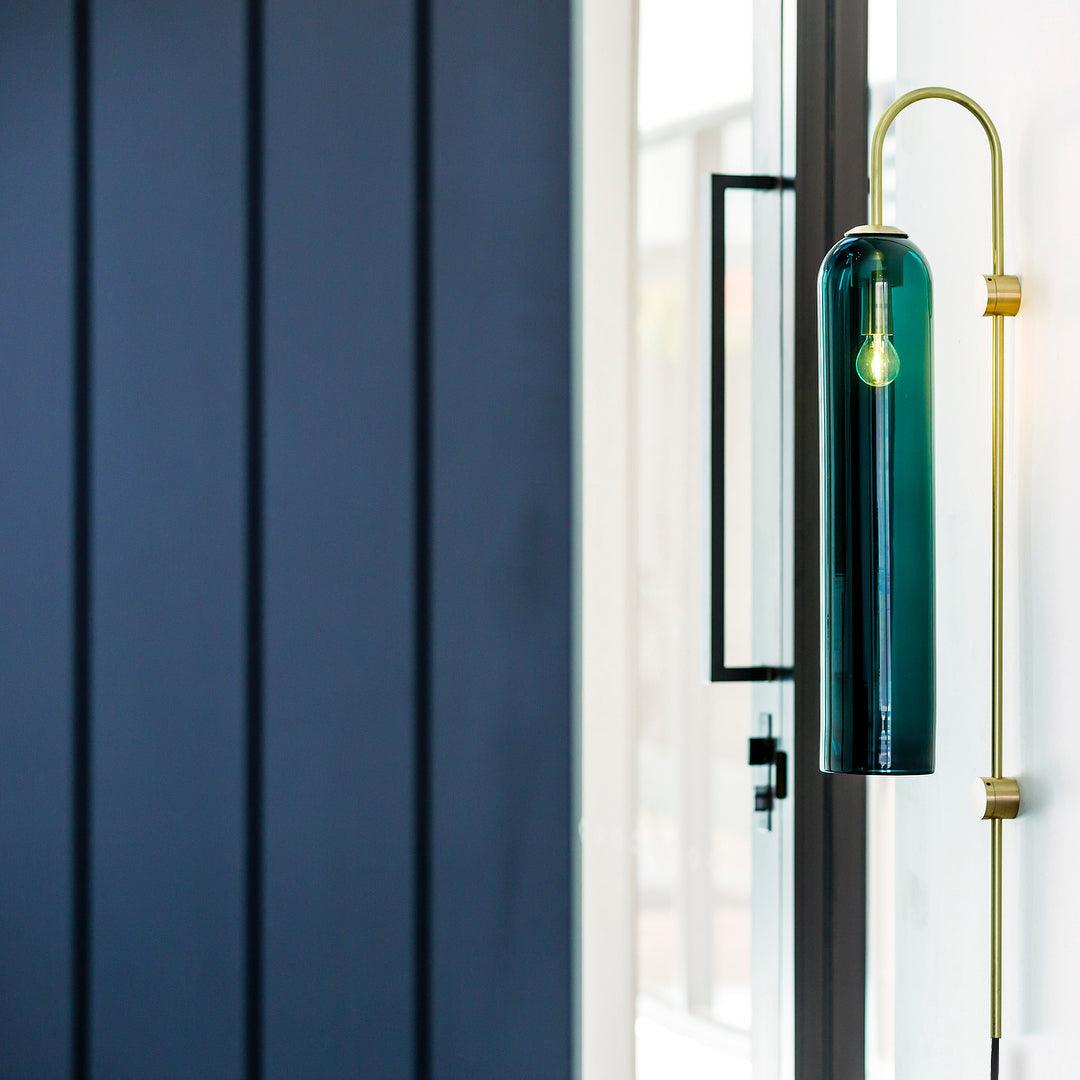 Tall dark teal wall lamp near a window