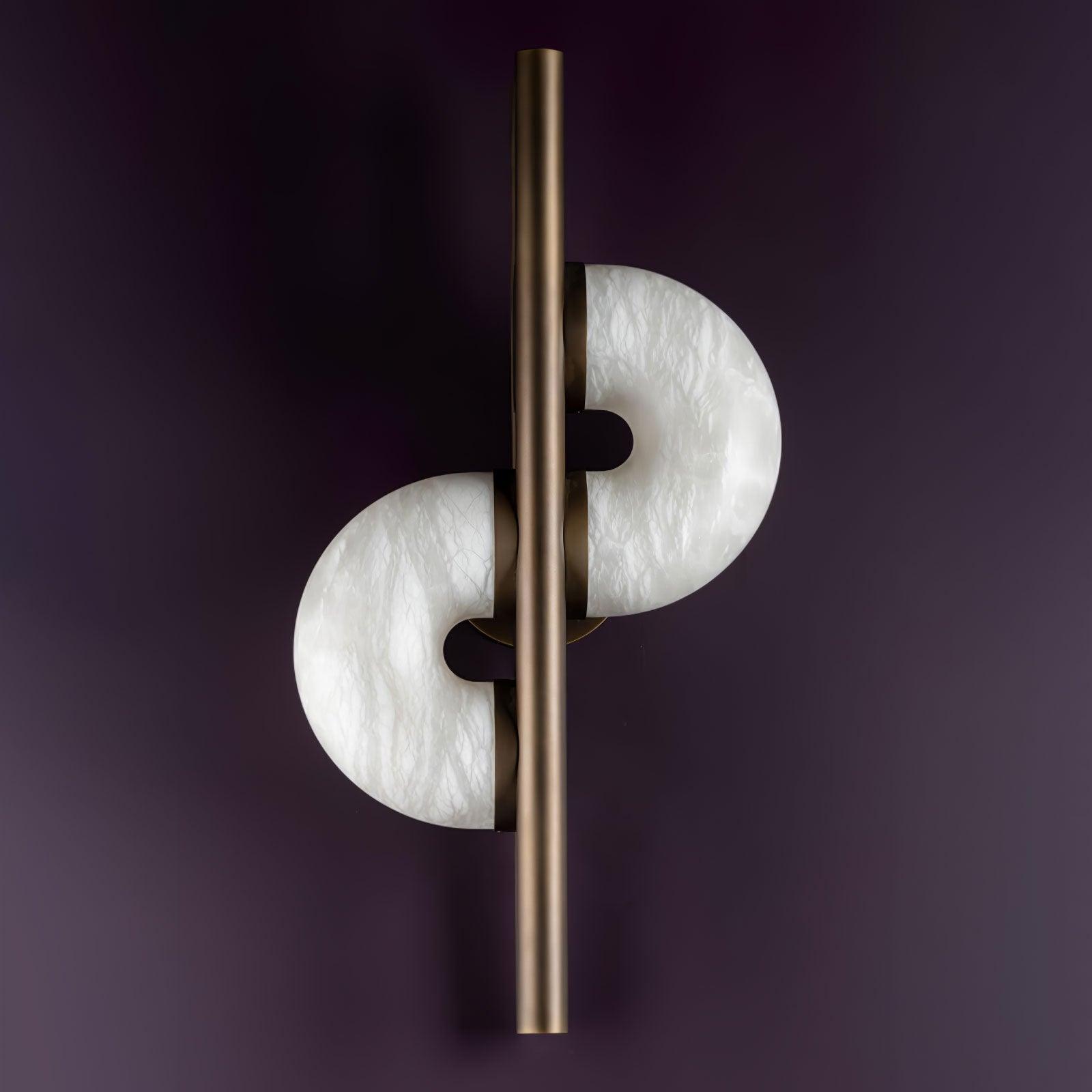 Unlit front view on purple wall, with staggered white veined discs, inner notches and bronze bar extending above and below