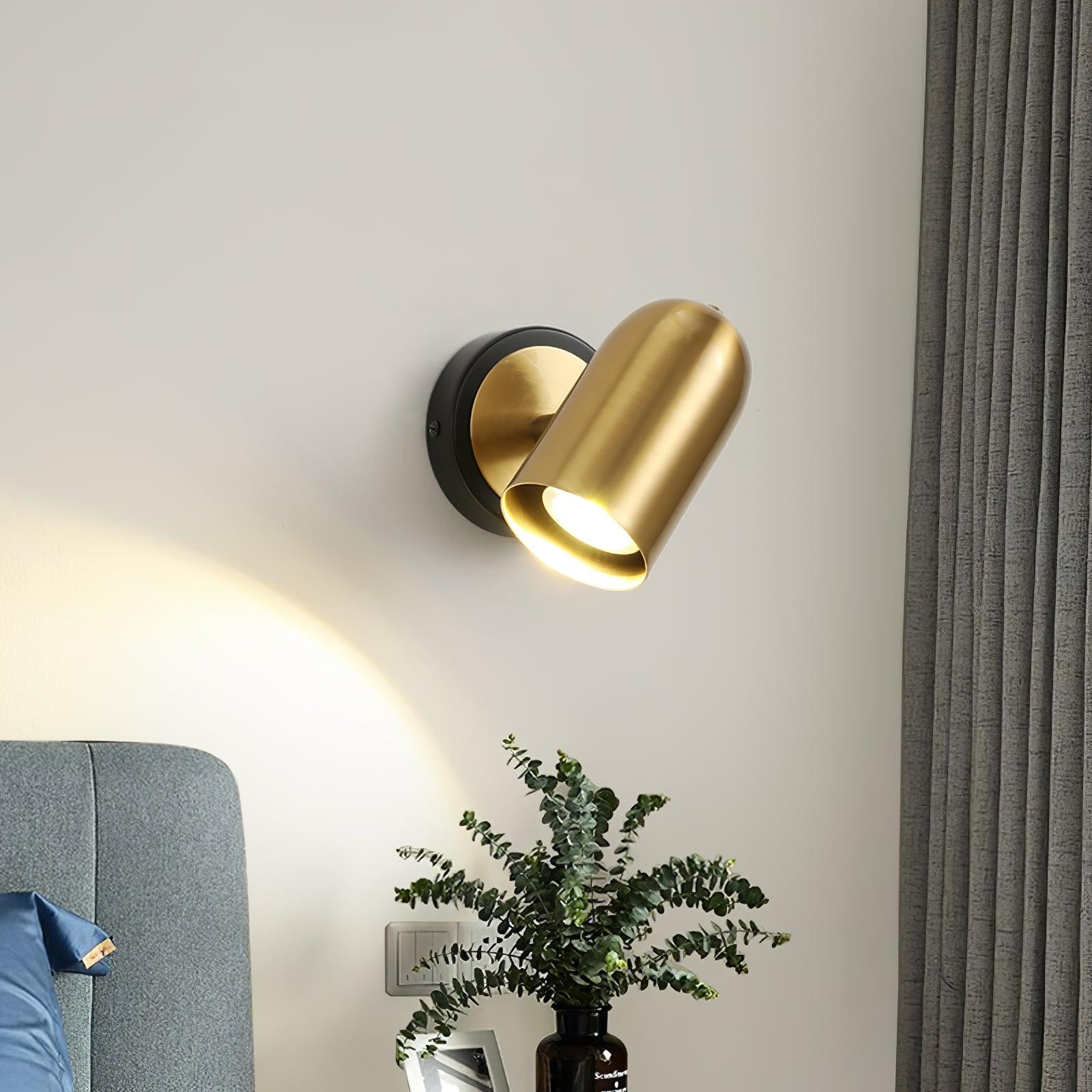 Gold wall lamp above a plant beside a blue headboard