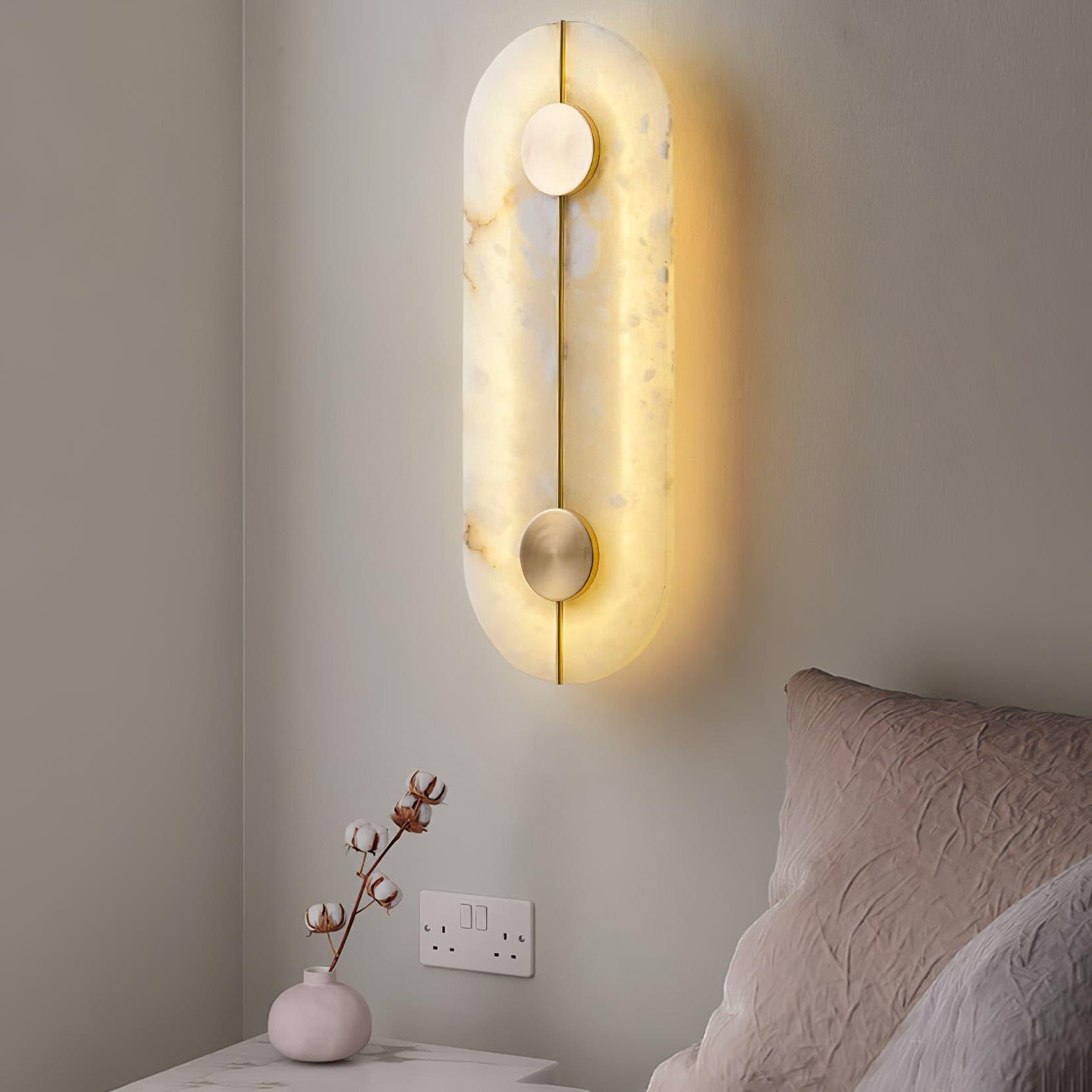 Capsule wall light above a bedside shelf