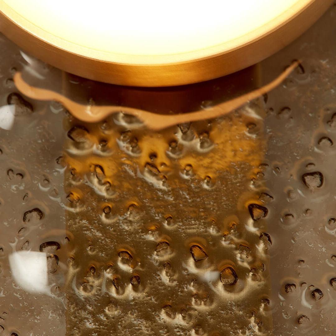 Macro view of bubble-like glass texture and gold-coloured reflections below a light rim