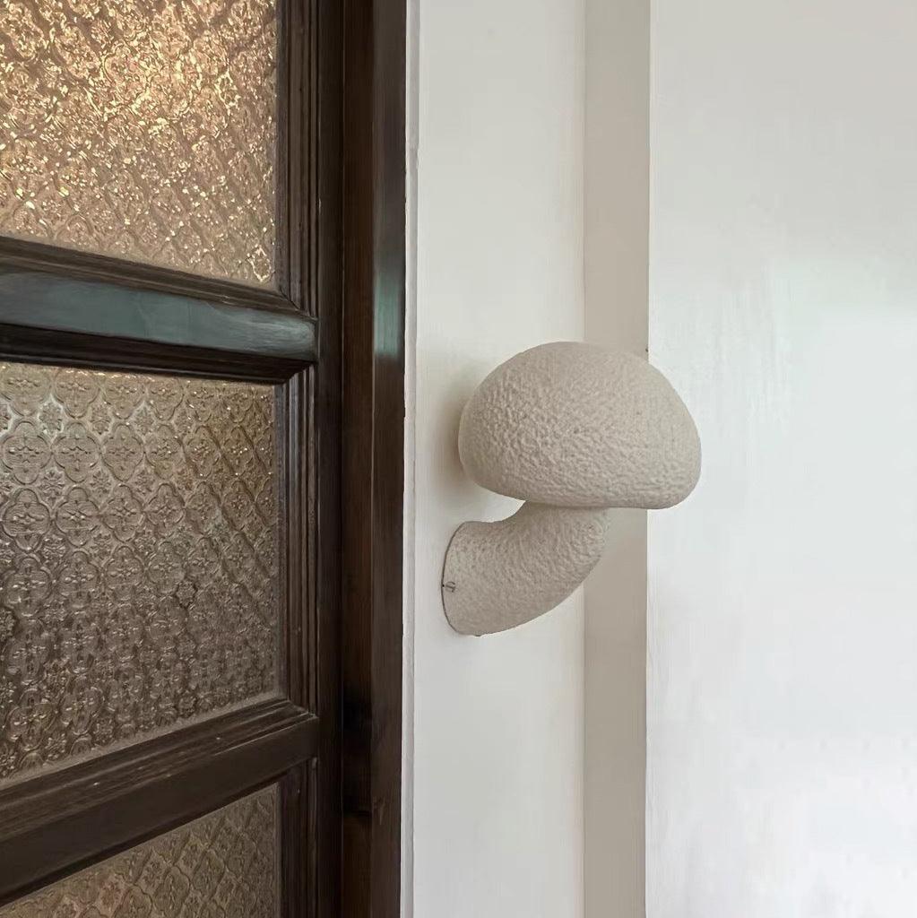 White resin wall light beside a patterned door