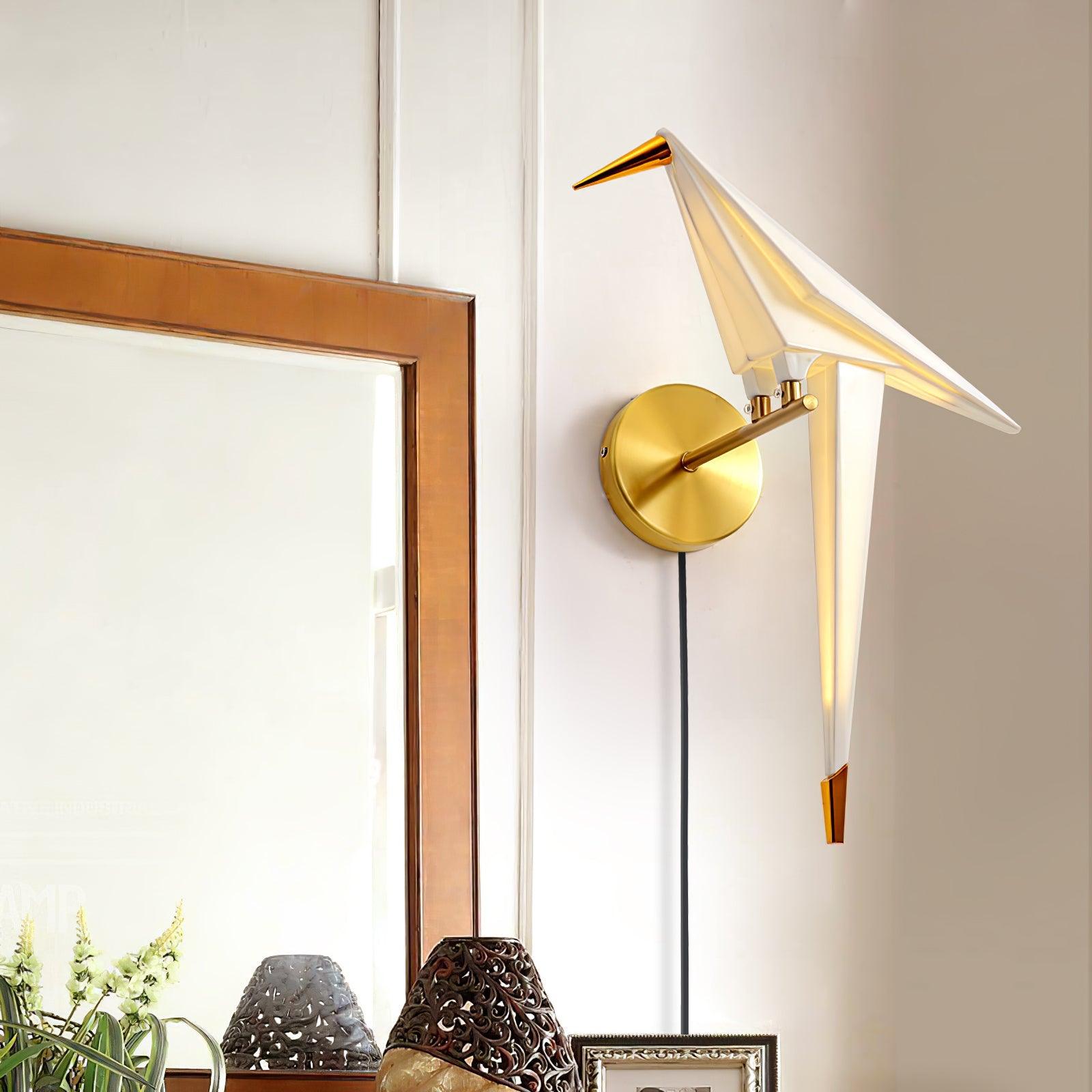 Gold and White bird wall lamp glowing beside a wood-framed mirror, with a round backplate, arm and Black cable