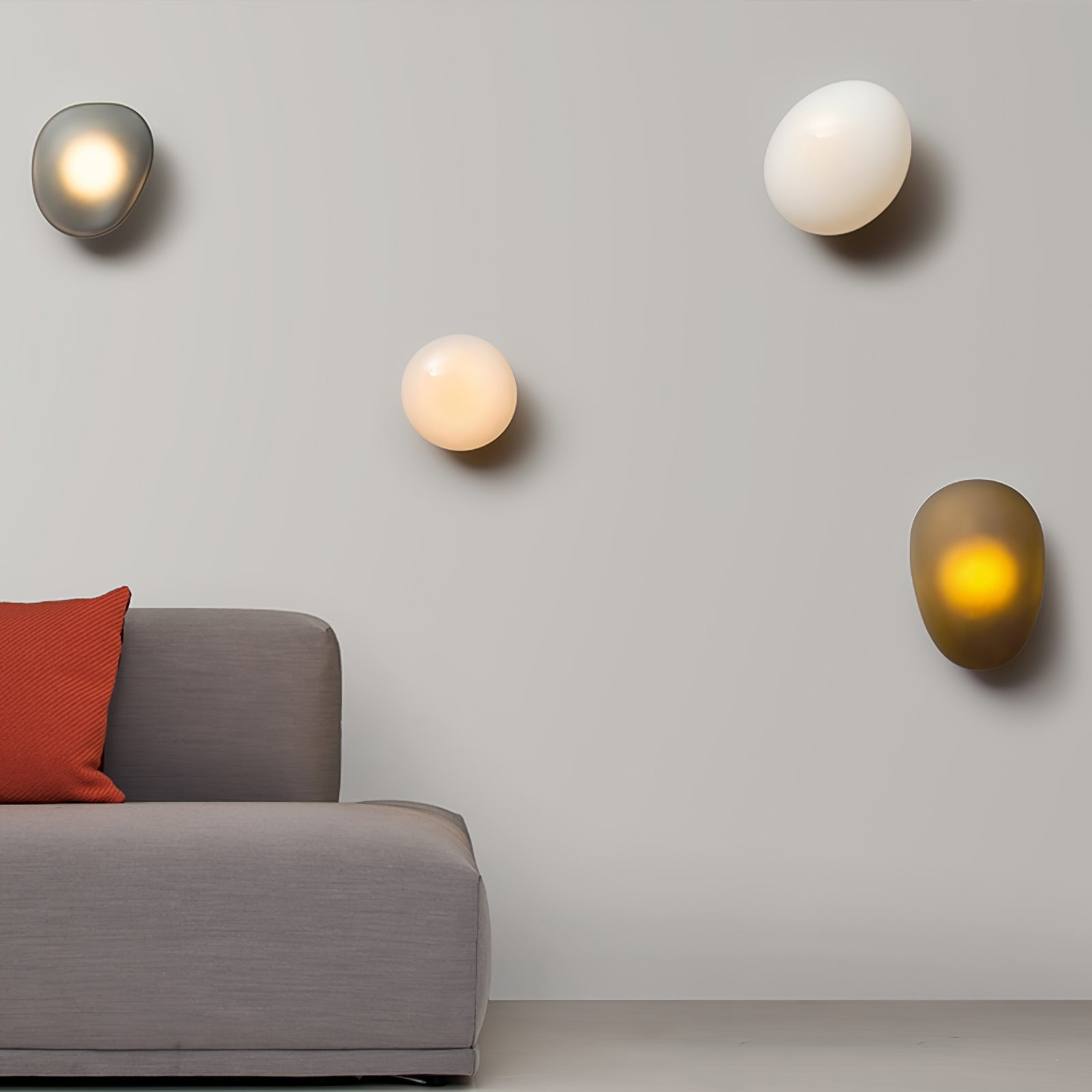 Four organic glass wall lights above a gray sofa with a red cushion