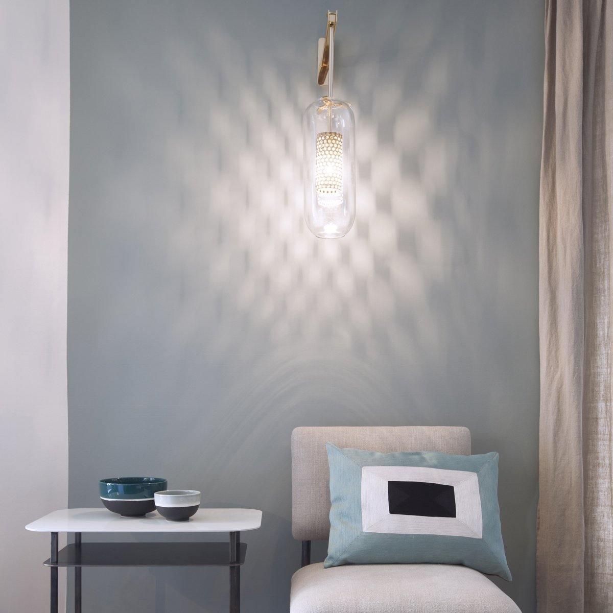 Illuminated glass wall light beside an upholstered chair and small table