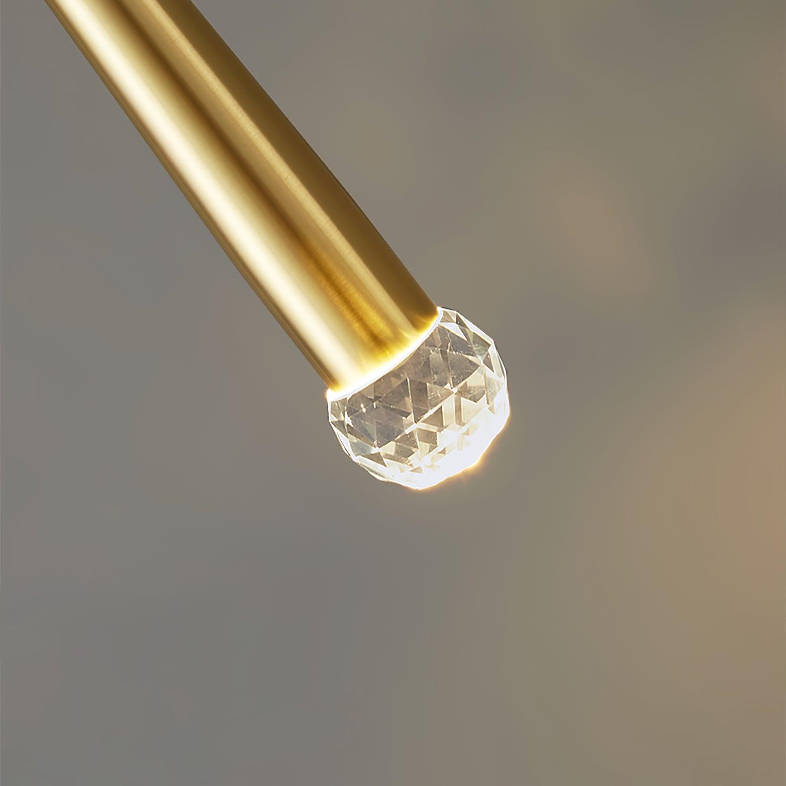 Close-up of a faceted clear crystal tip illuminated at the end of a brass-tone tapered body