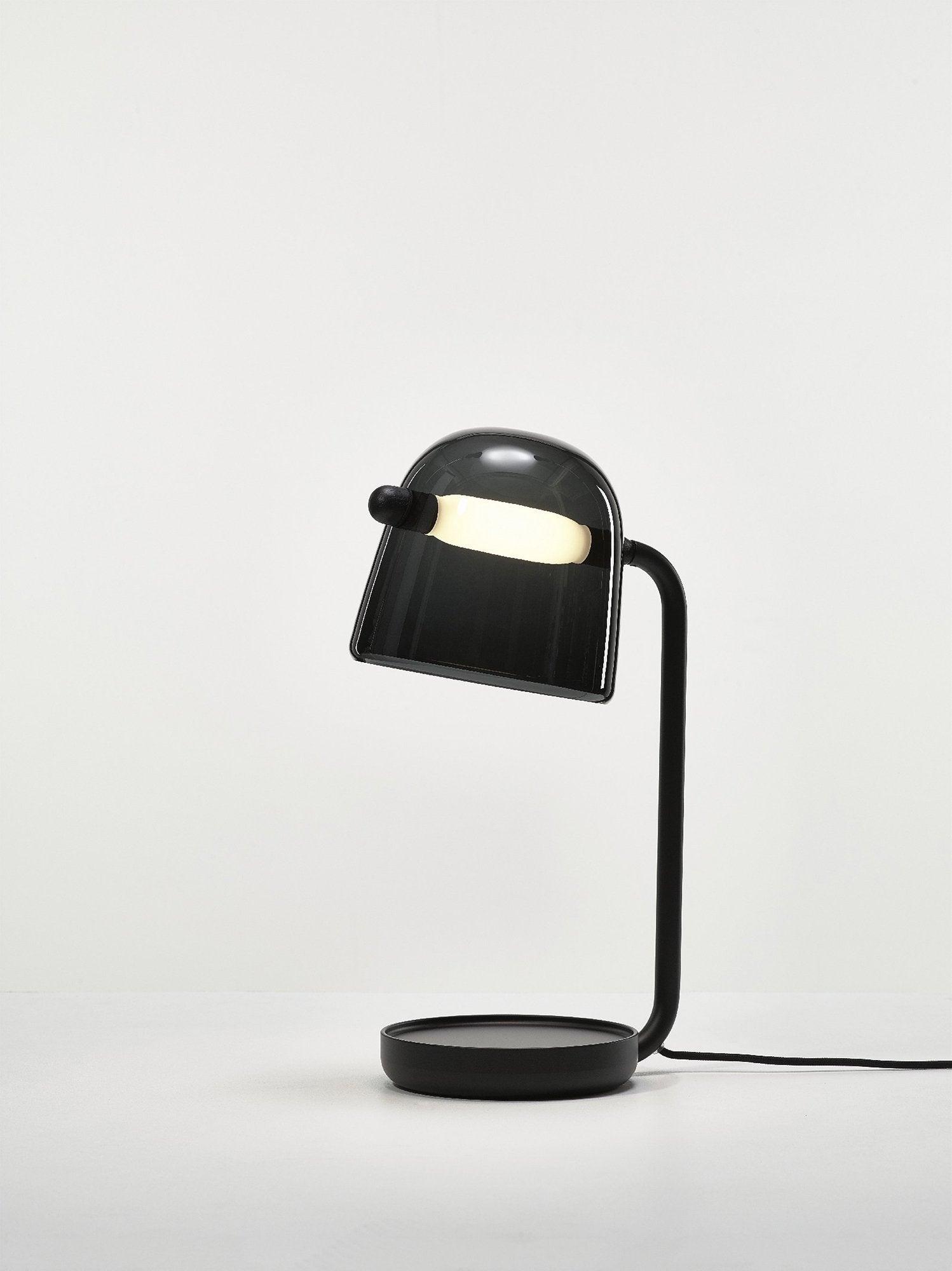 Black Mona table lamp with power cable on a pale surface